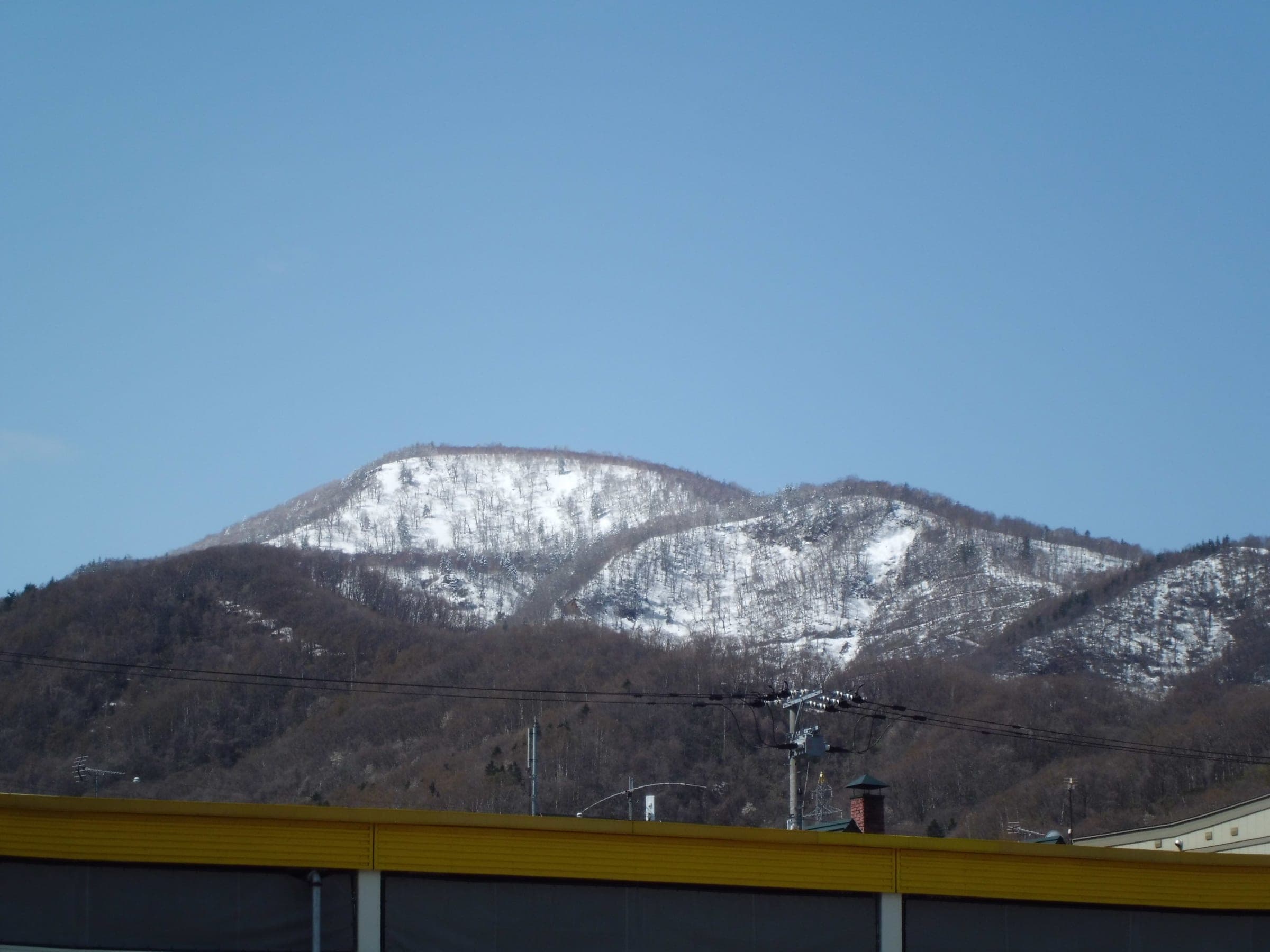 Late snow covers the upper slopes of Haruka-yama and the neighbouring ridge above bare forest