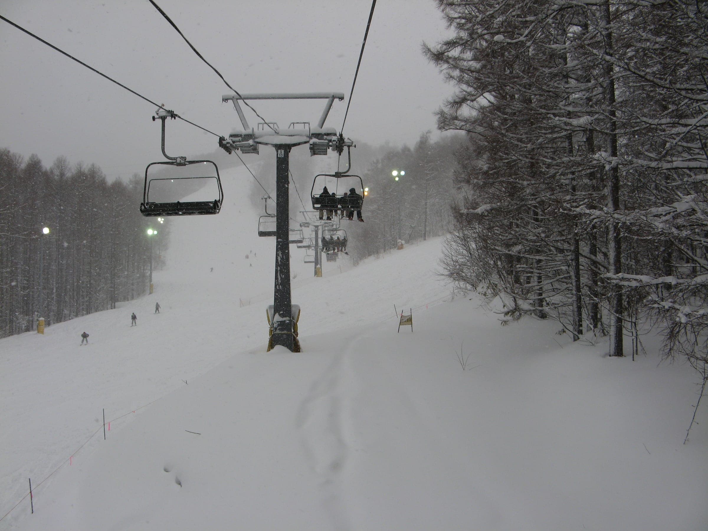 A chairlift climbs through snowy birch forest at the Onze ski area on Haruka-yama's lower slopes