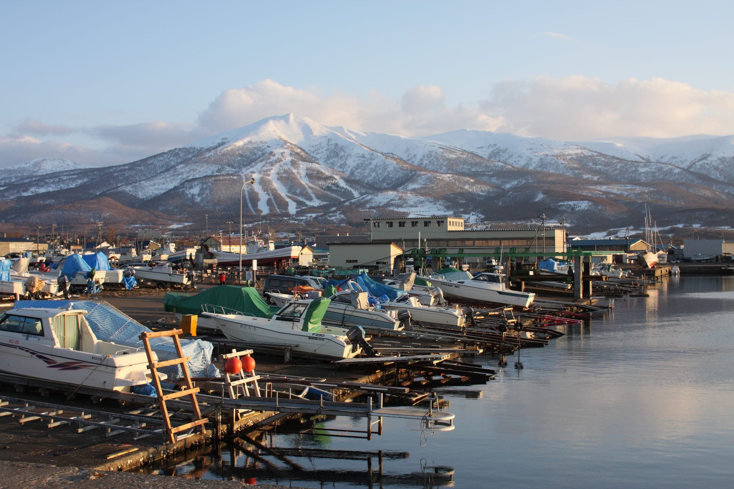 Fishing boats in Iwanai harbour with snow-covered Iwanai-dake rising behind