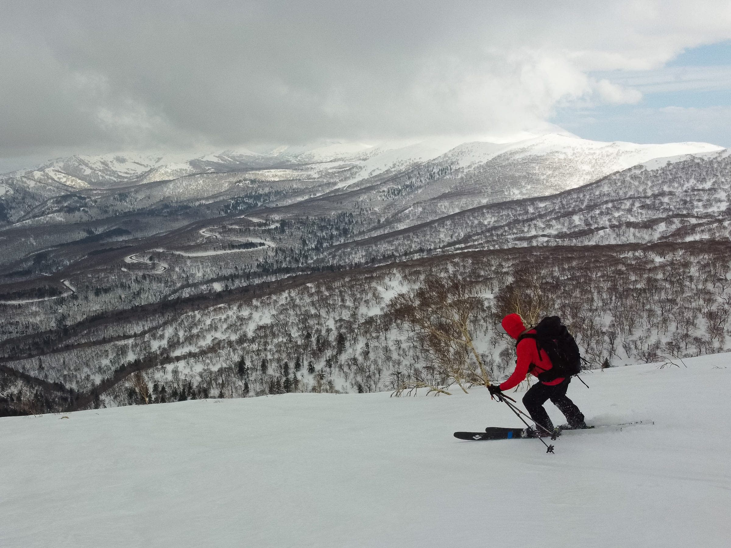 A skier on Iwanai-dake's northeast ridge looks out over forested hills