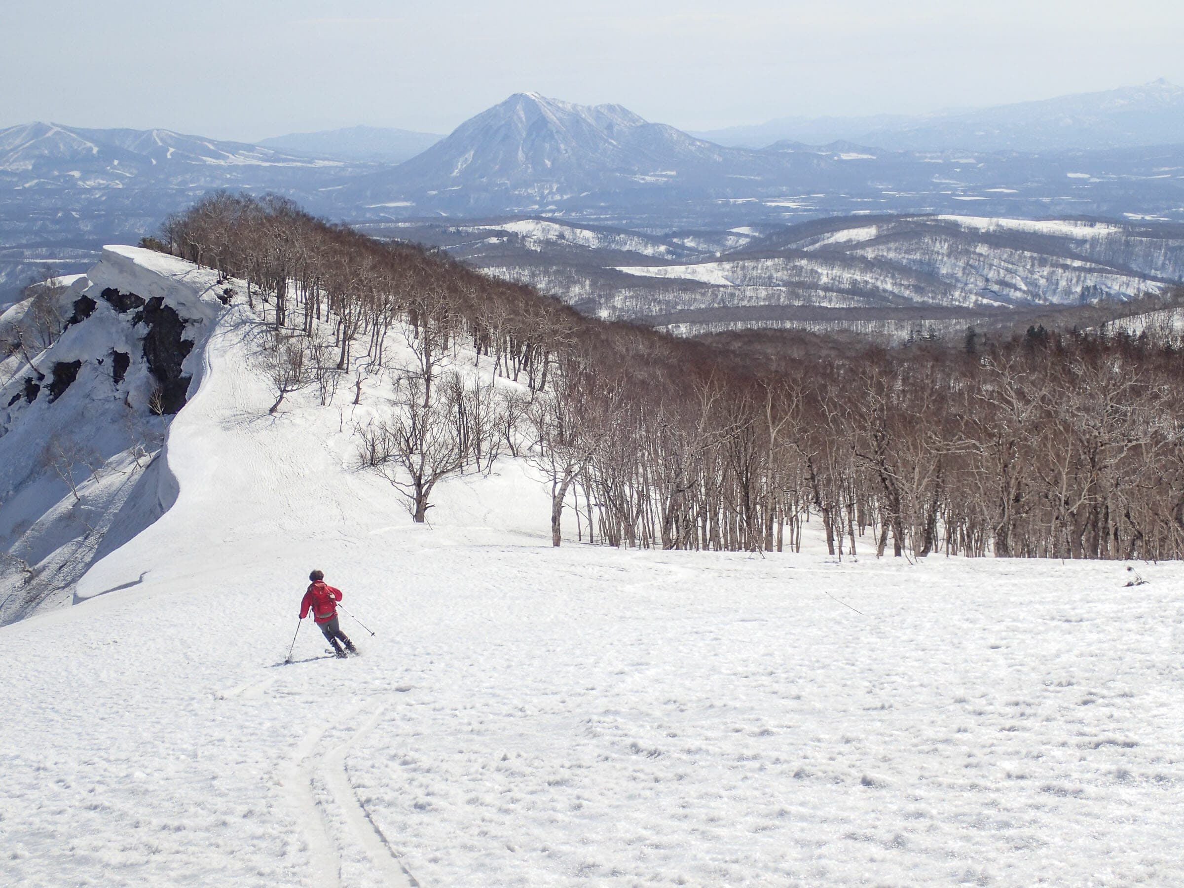 A skier crosses a broad snowfield on the Muine-yama to Kimobetsu-dake traverse