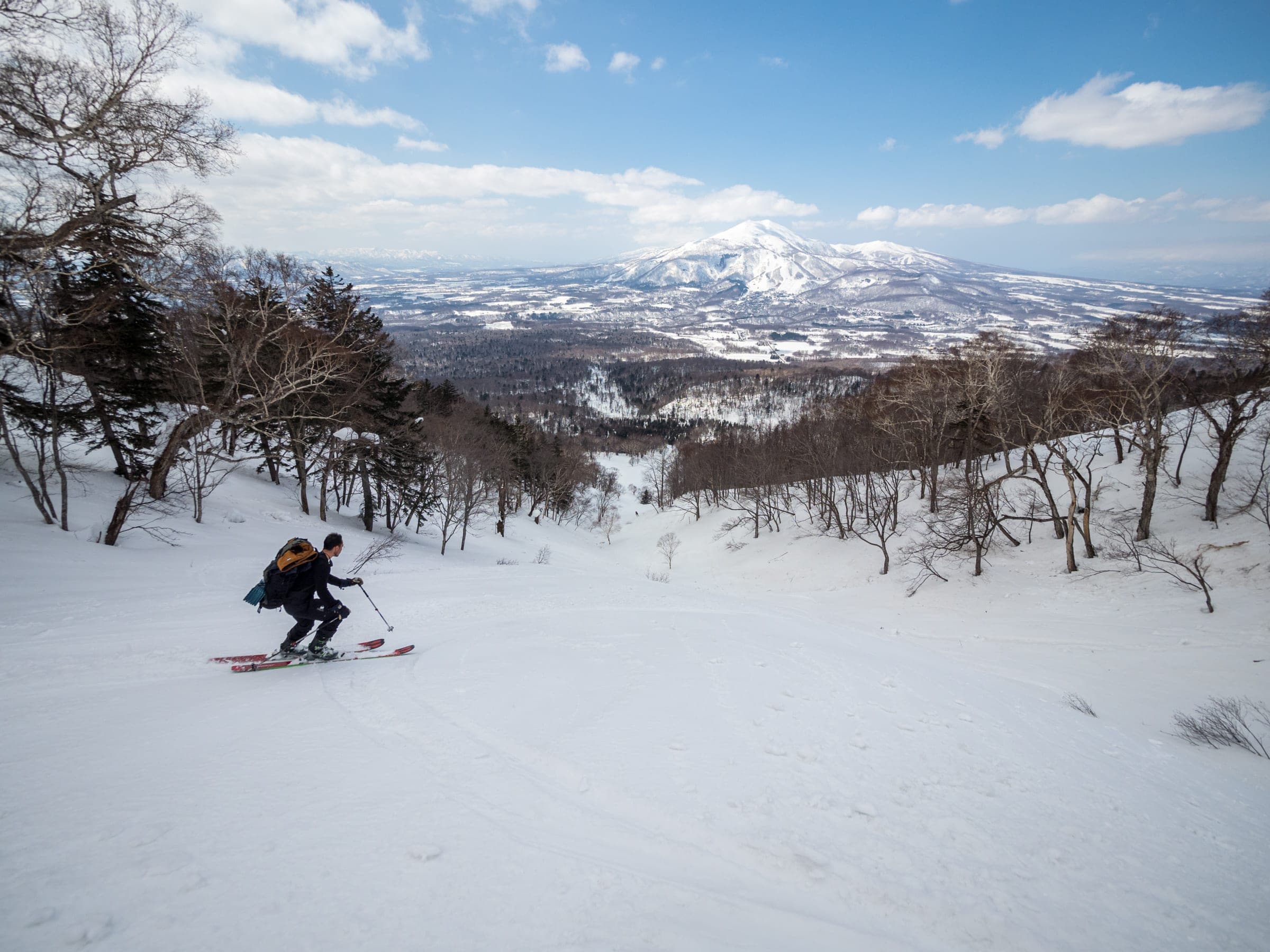 A skier turns on open slopes of the Hirafu route on Mt. Yotei with the Niseko range beyond