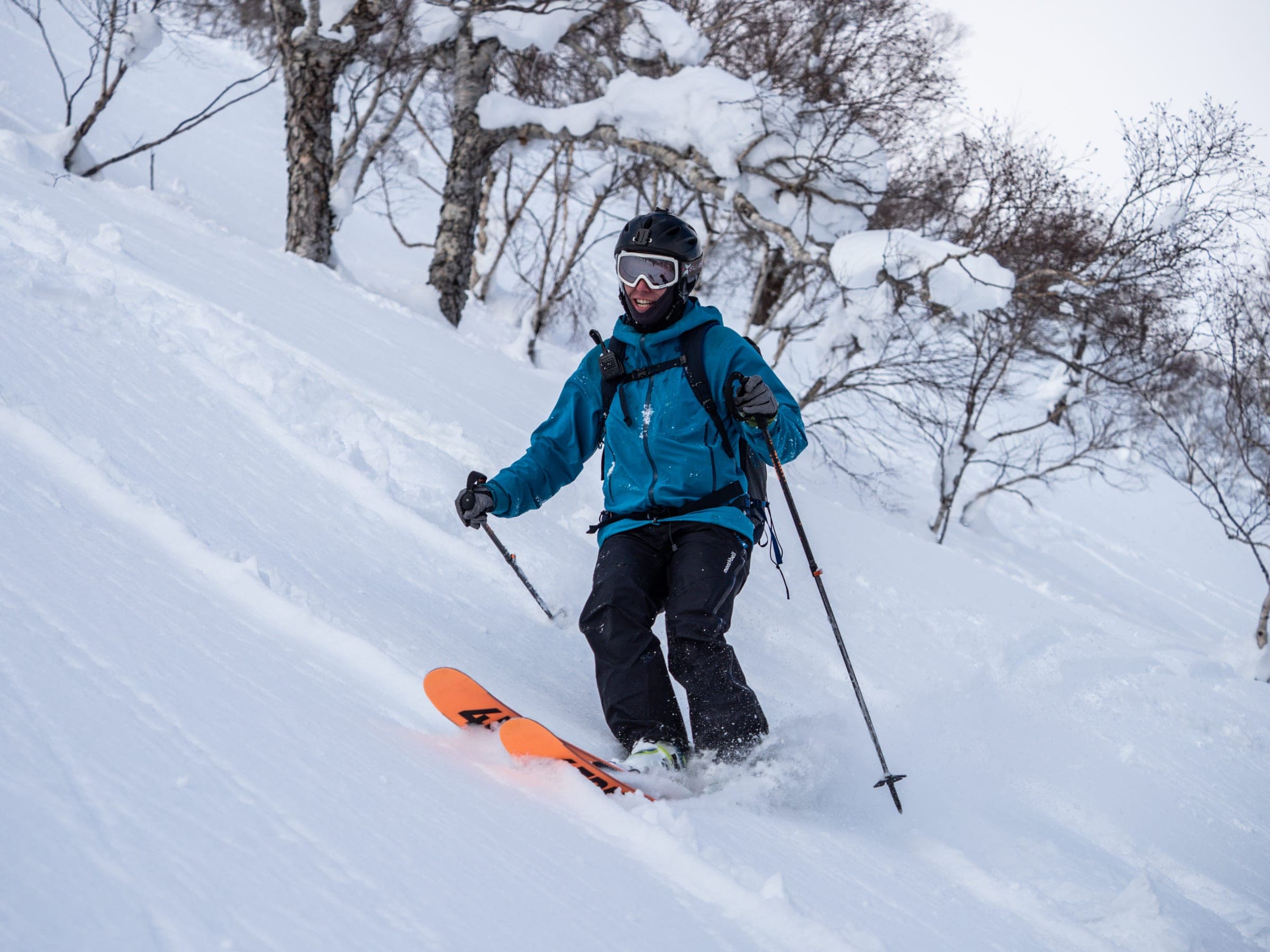 A skier in a teal jacket turns through deep powder on the southeast face of Nitonupuri