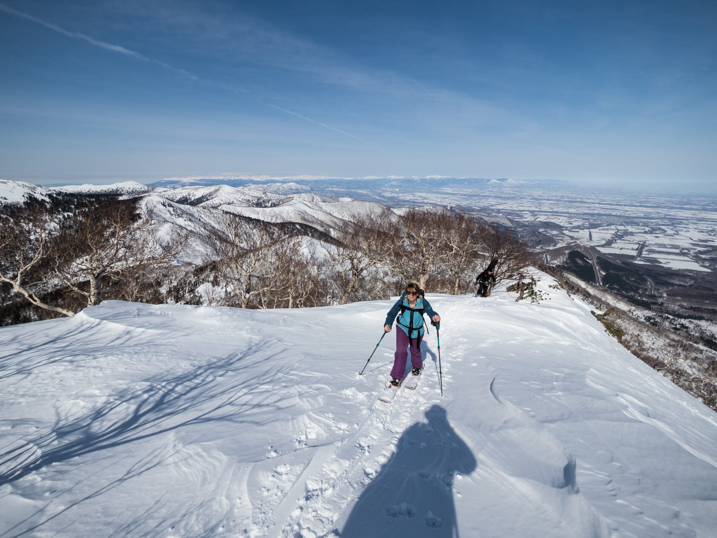 A ski tourer climbs the north ridge of Pekerebetsu-dake with the Tokachi plain behind