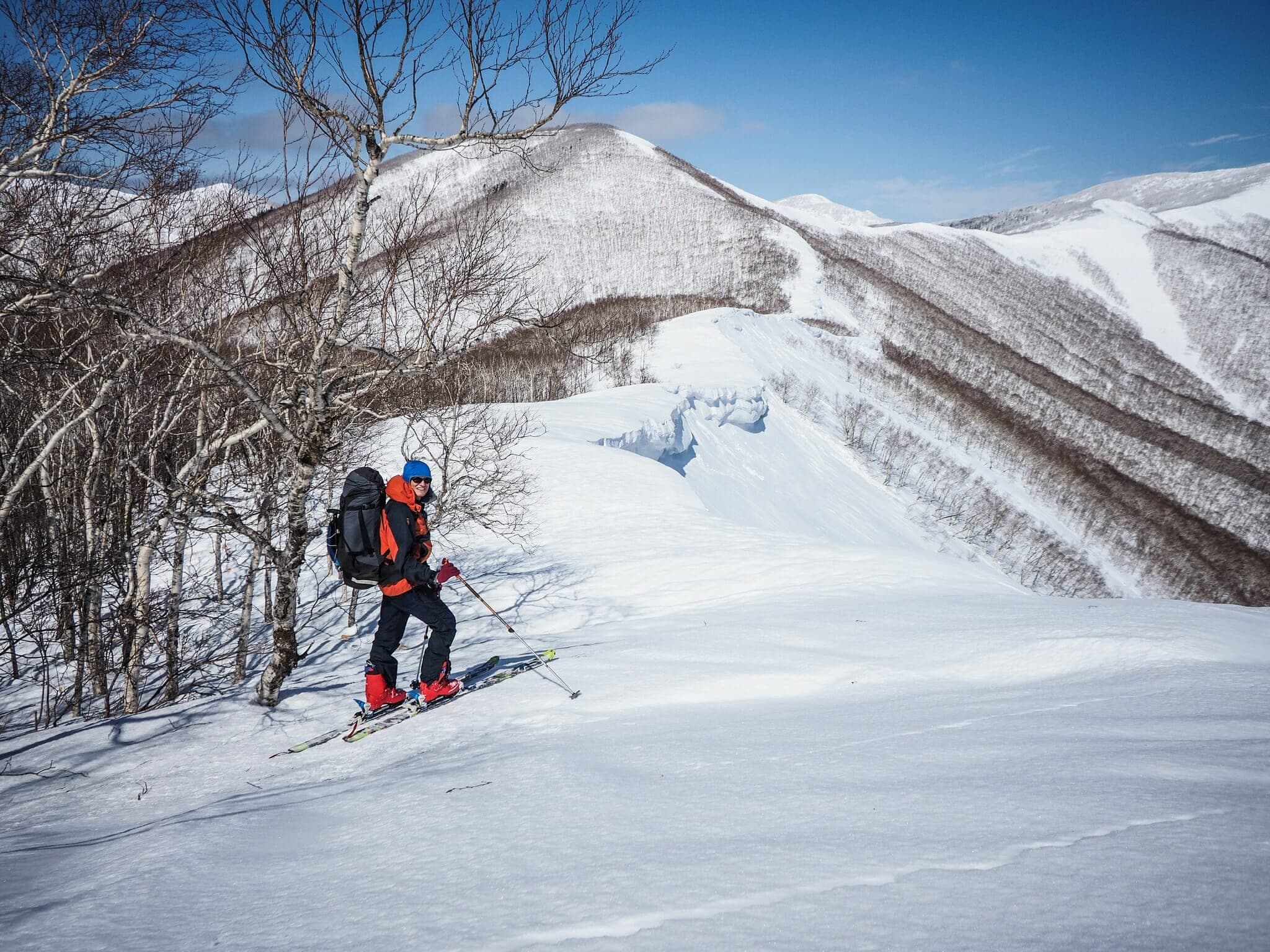 A ski tourer climbs the ridge from Karikachi Pass toward Sahoro-dake