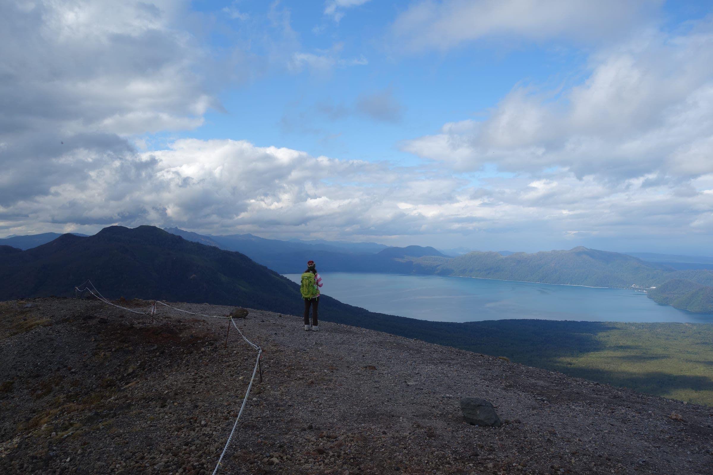 A hiker stands on the crater rim of Tarumae-zan above Lake Shikotsu