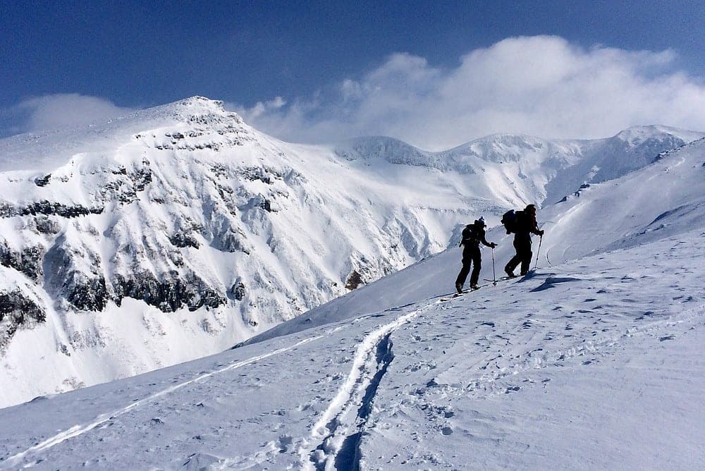 Ski tourers skin up a snowy ridge on Sandan-yama in the Tokachi range