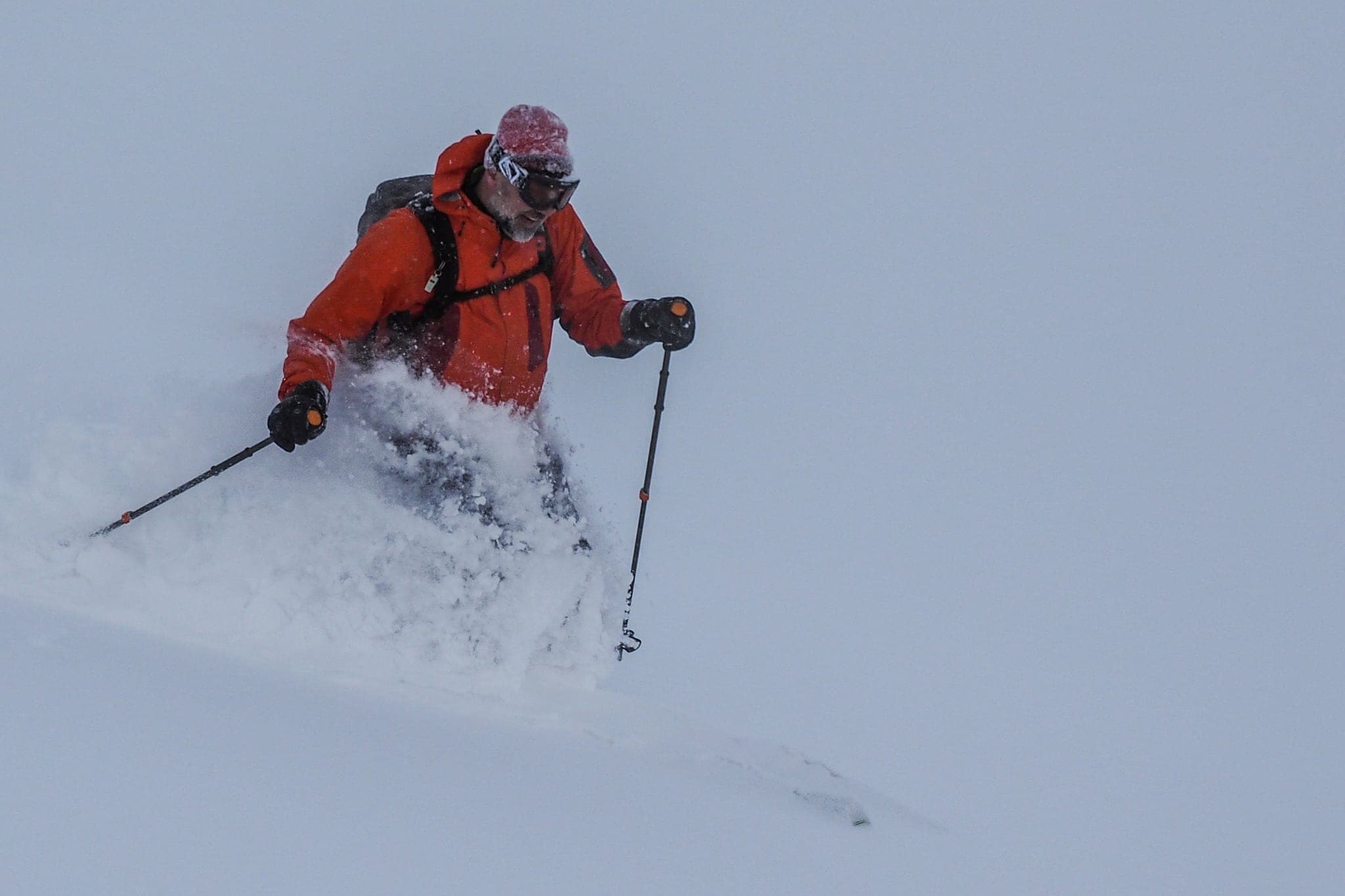 A skier in a red jacket kicks up powder on the Kabawara ridge of Maetokachi-dake