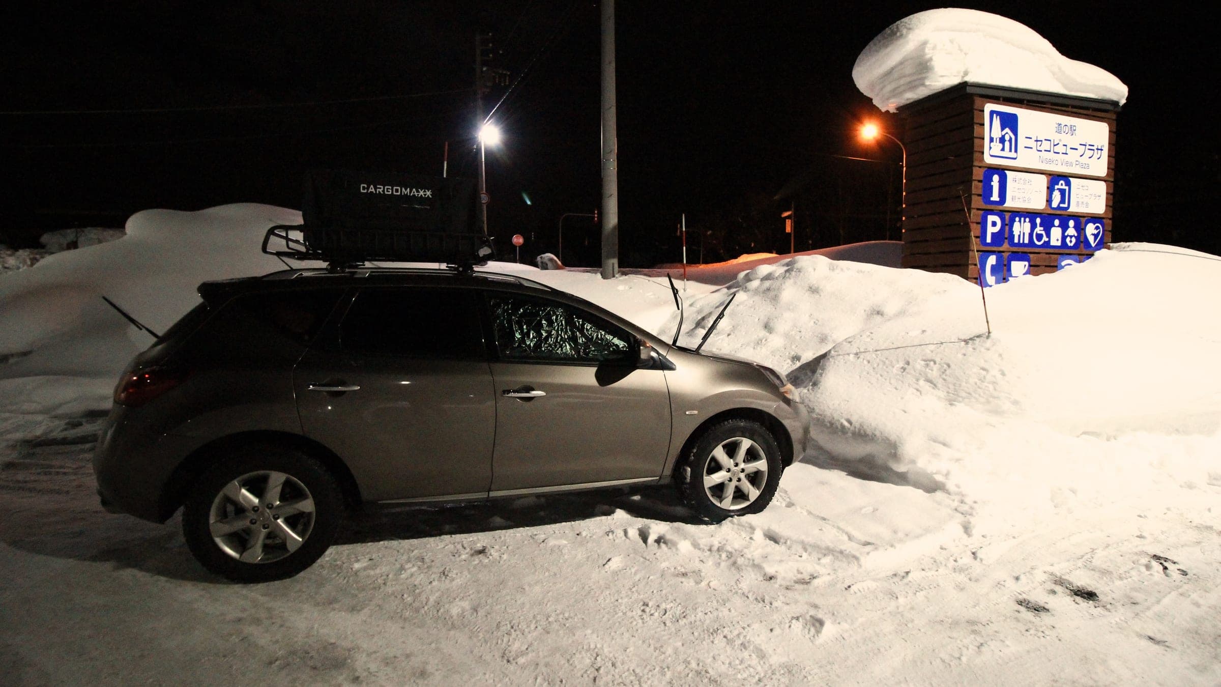 An SUV parked for the night in deep snow at Michi-no-eki Niseko View Plaza