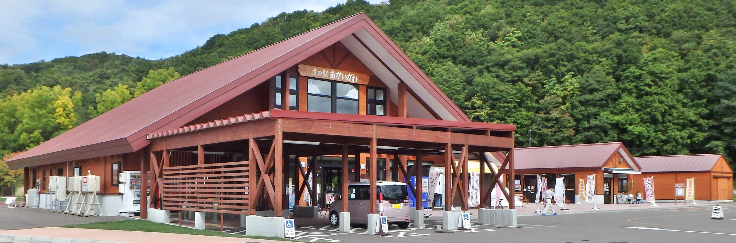 The red timber building of Michi-no-eki Akaigawa against a forested hill
