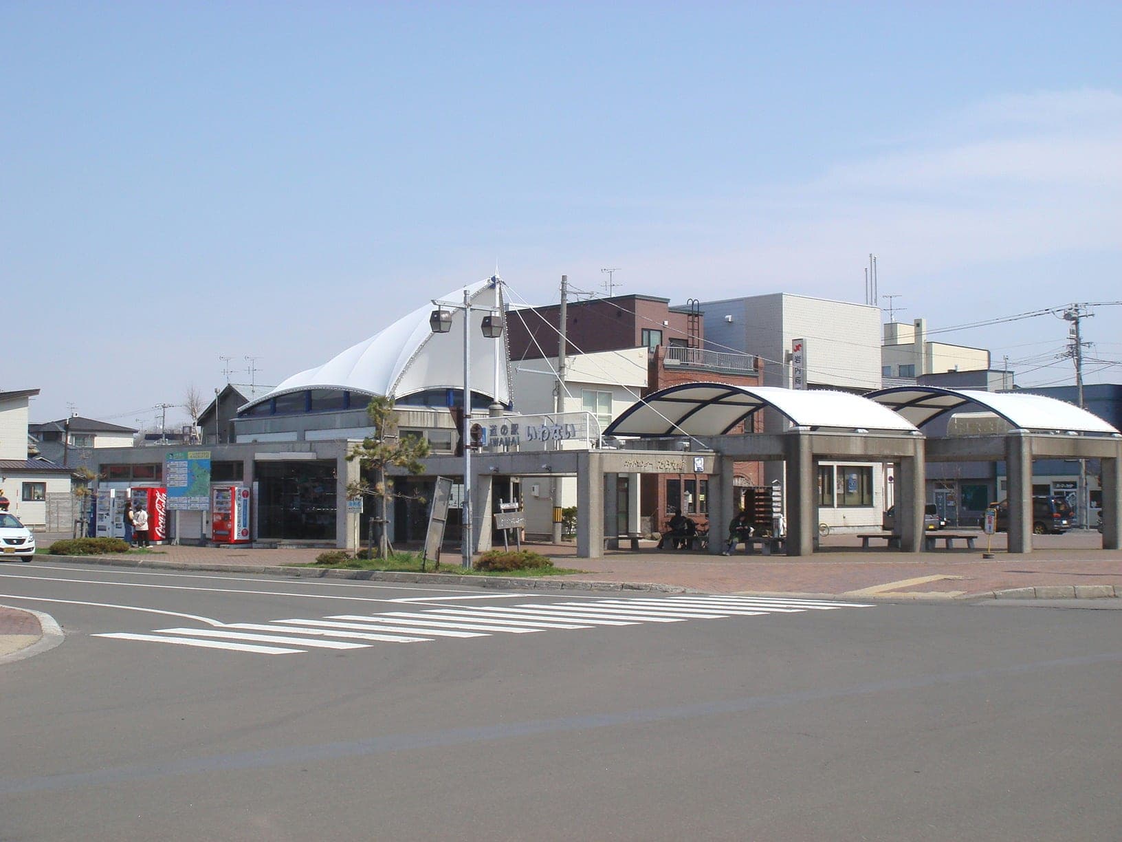 The white canopy roofs of Michi-no-eki Iwanai beside the road