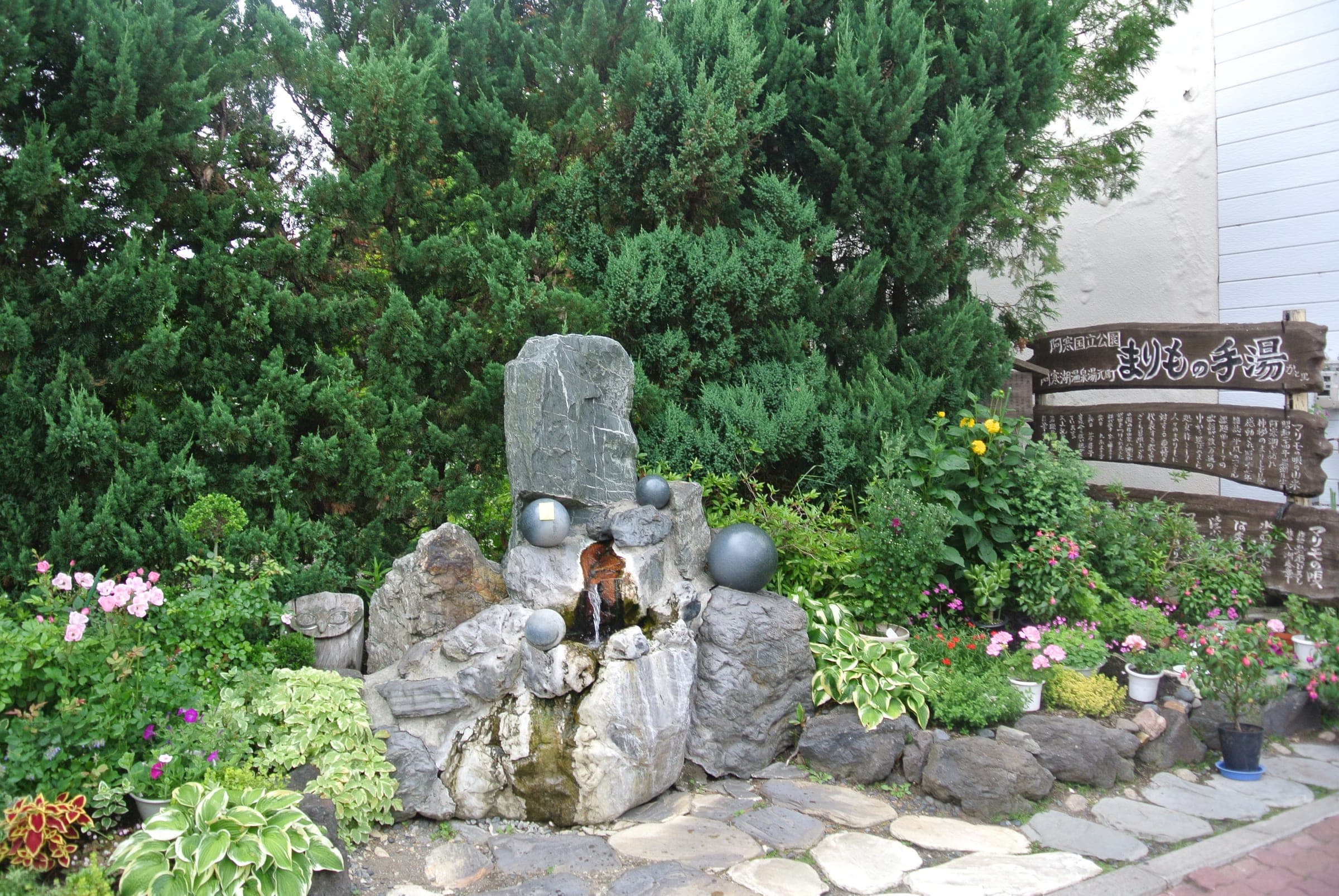 A stone fountain and garden mark the Akanko Onsen hot spring in summer