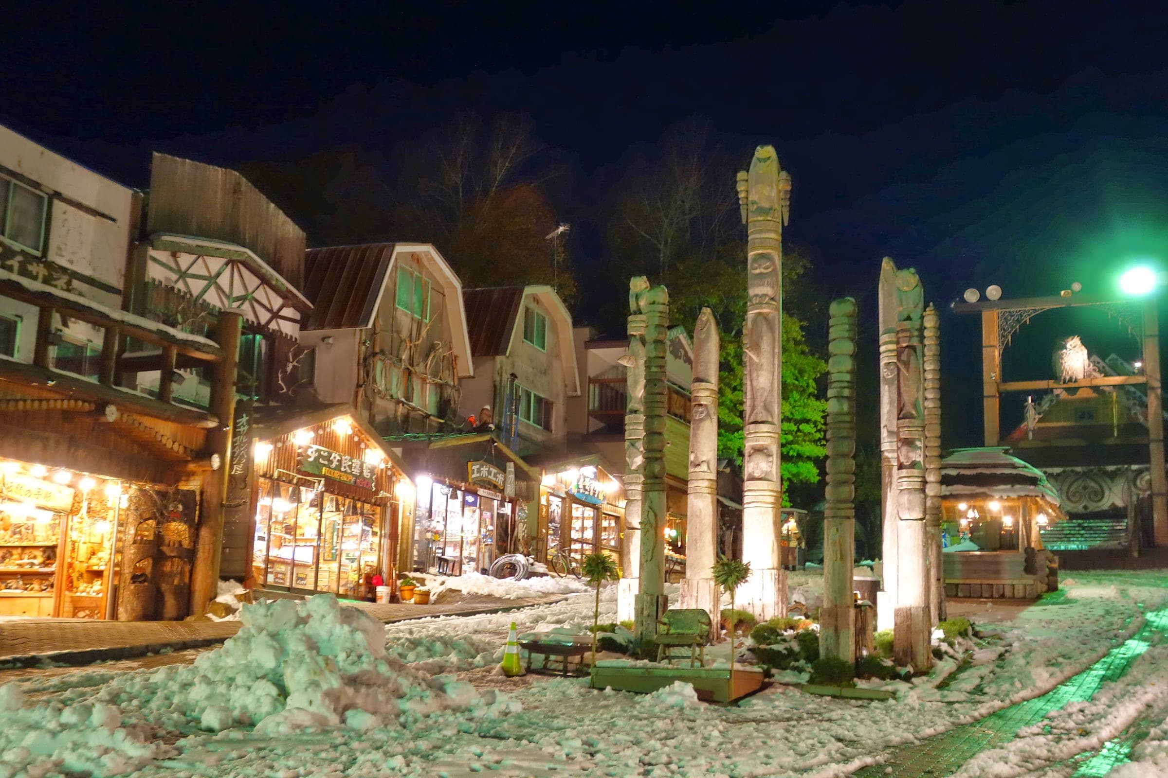Carved Ainu poles line a lit street in Akanko Onsen at night