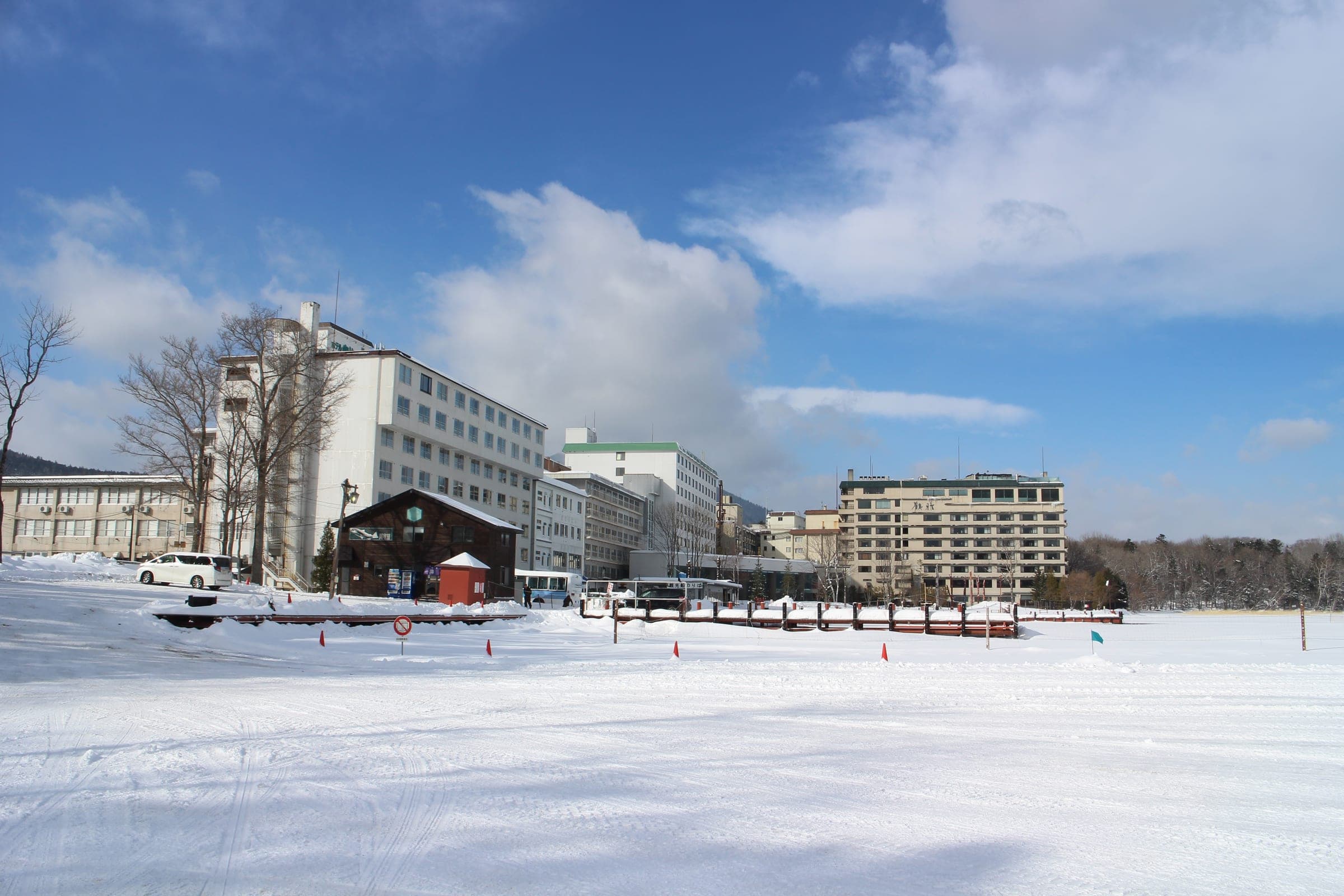 Lakeside hotels at Akanko Onsen stand behind the frozen, snow-covered surface of Lake Akan