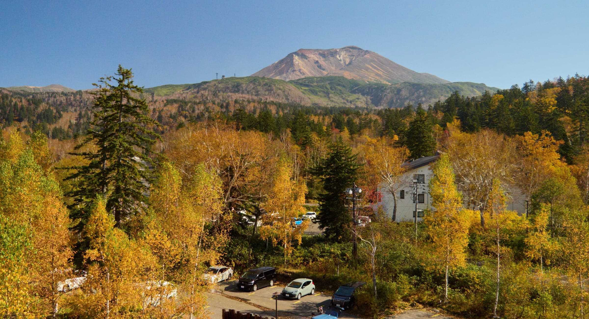 Autumn birch and larch frame Mt. Asahidake above the Asahidake Onsen hamlet
