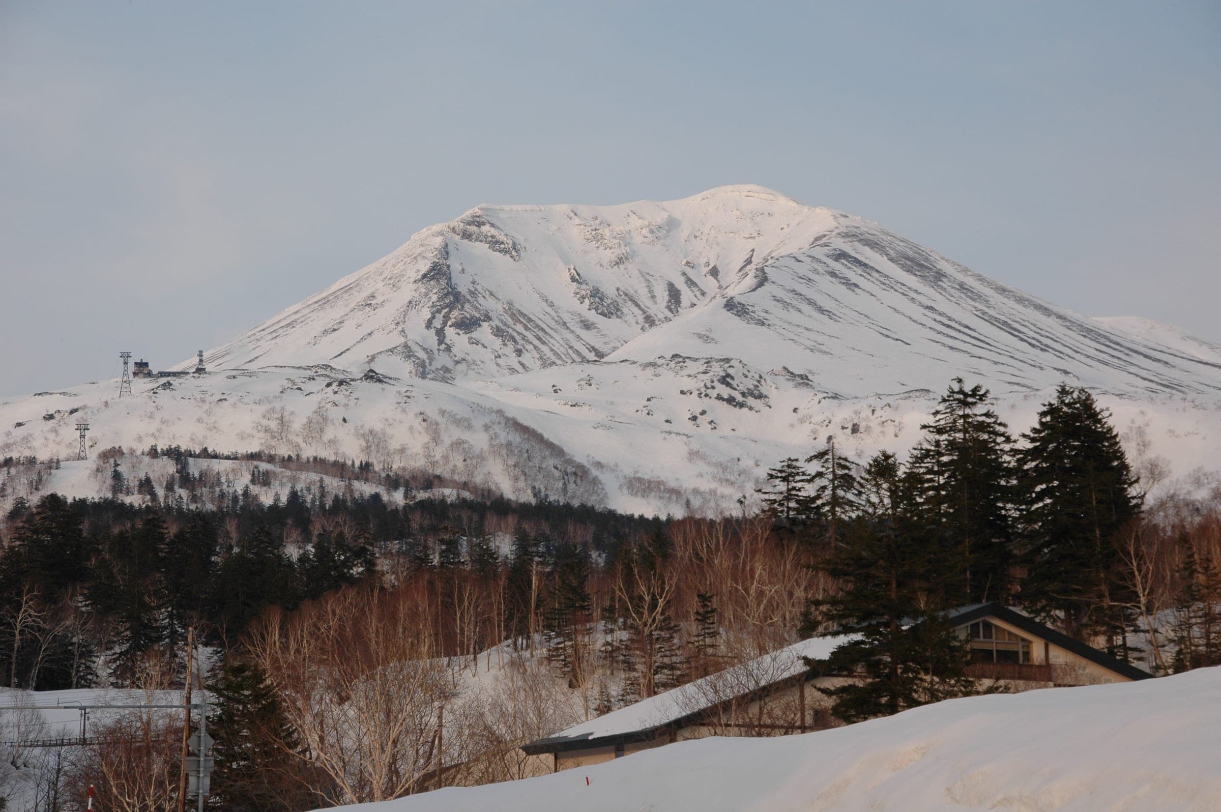 Snow-covered Mt. Asahidake rises behind the inns of Asahidake Onsen in winter