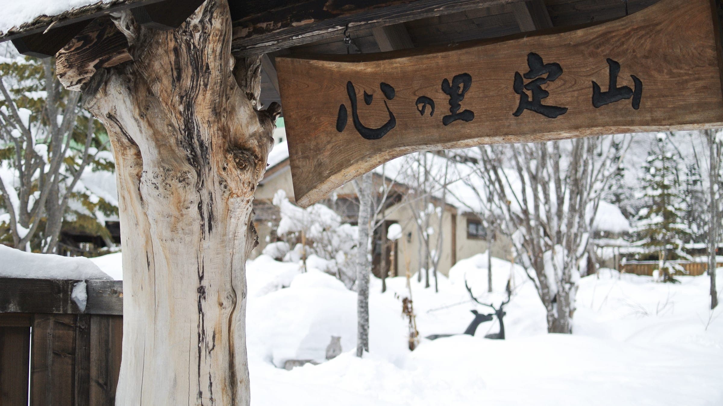 A carved wooden sign for Jozankei hangs above deep snow