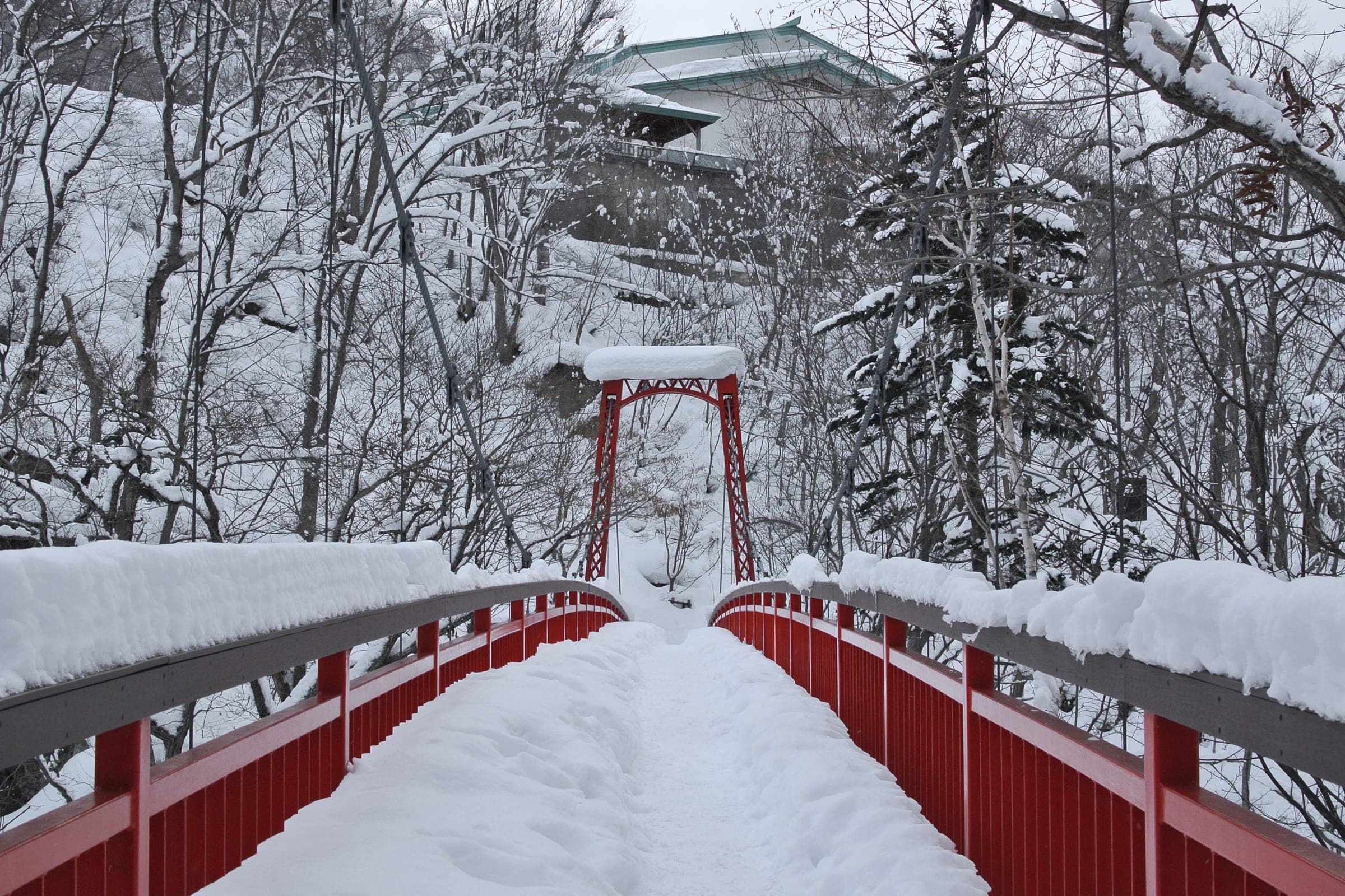 Snow covers the red railings of a footbridge in Jozankei Onsen