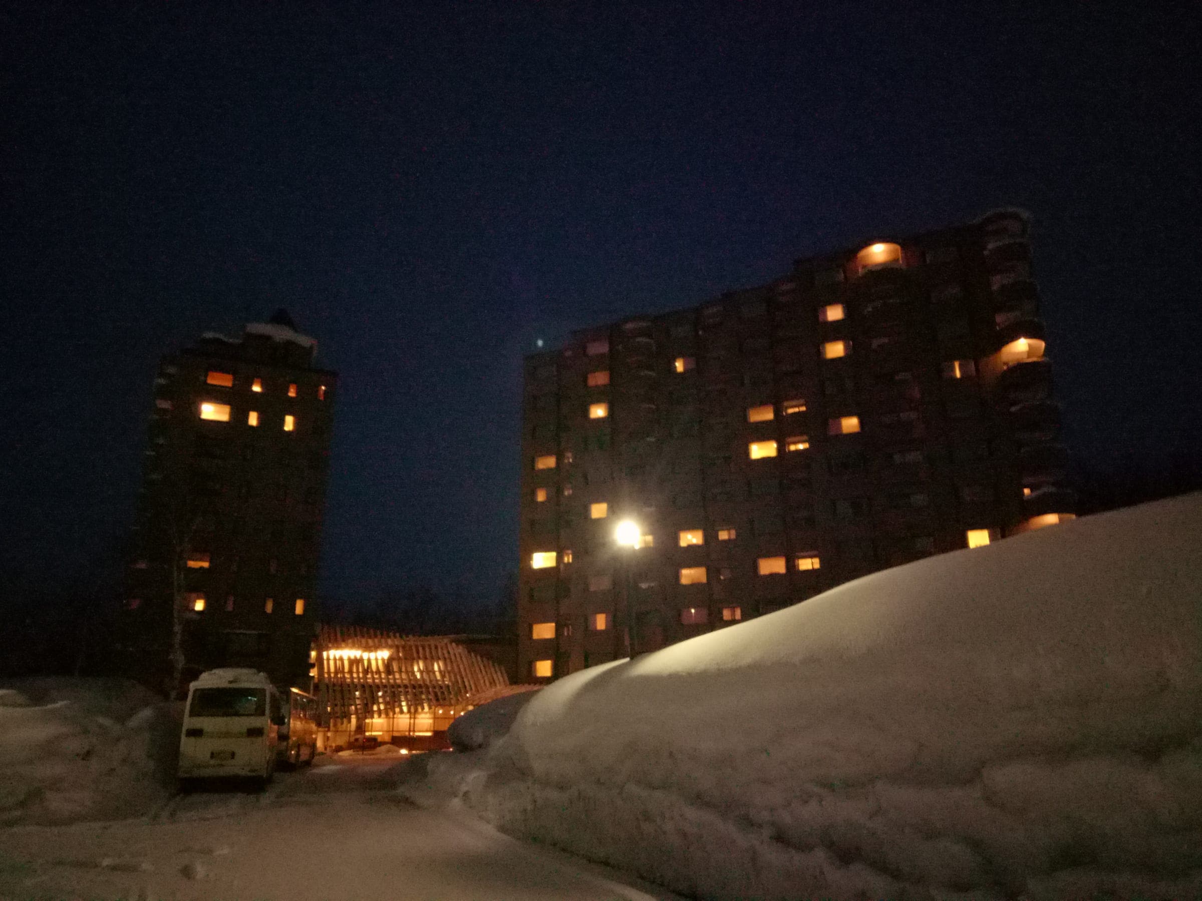 Deep snow banks line the road below lit hotel towers at Niseko Konbu Onsen, near Hotel Kanronomori