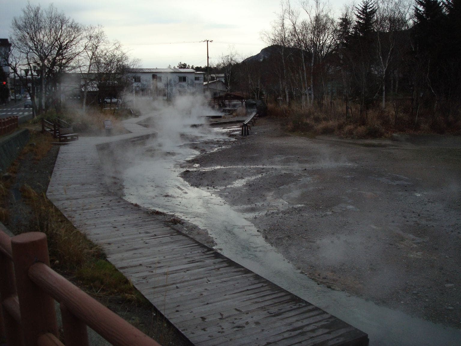 A hot river steams beside a boardwalk in Kawayu Onsen