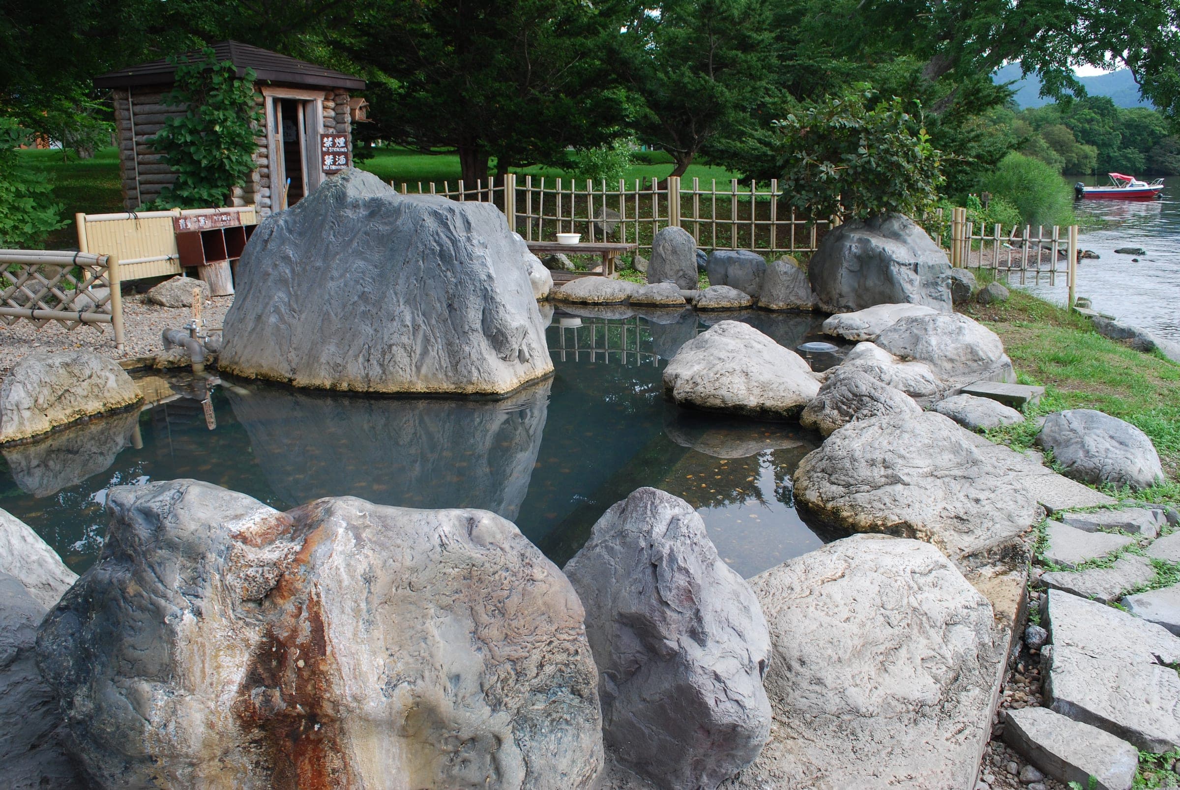 Large boulders ring the Kotan-no-yu pool on the Lake Kussharo shore