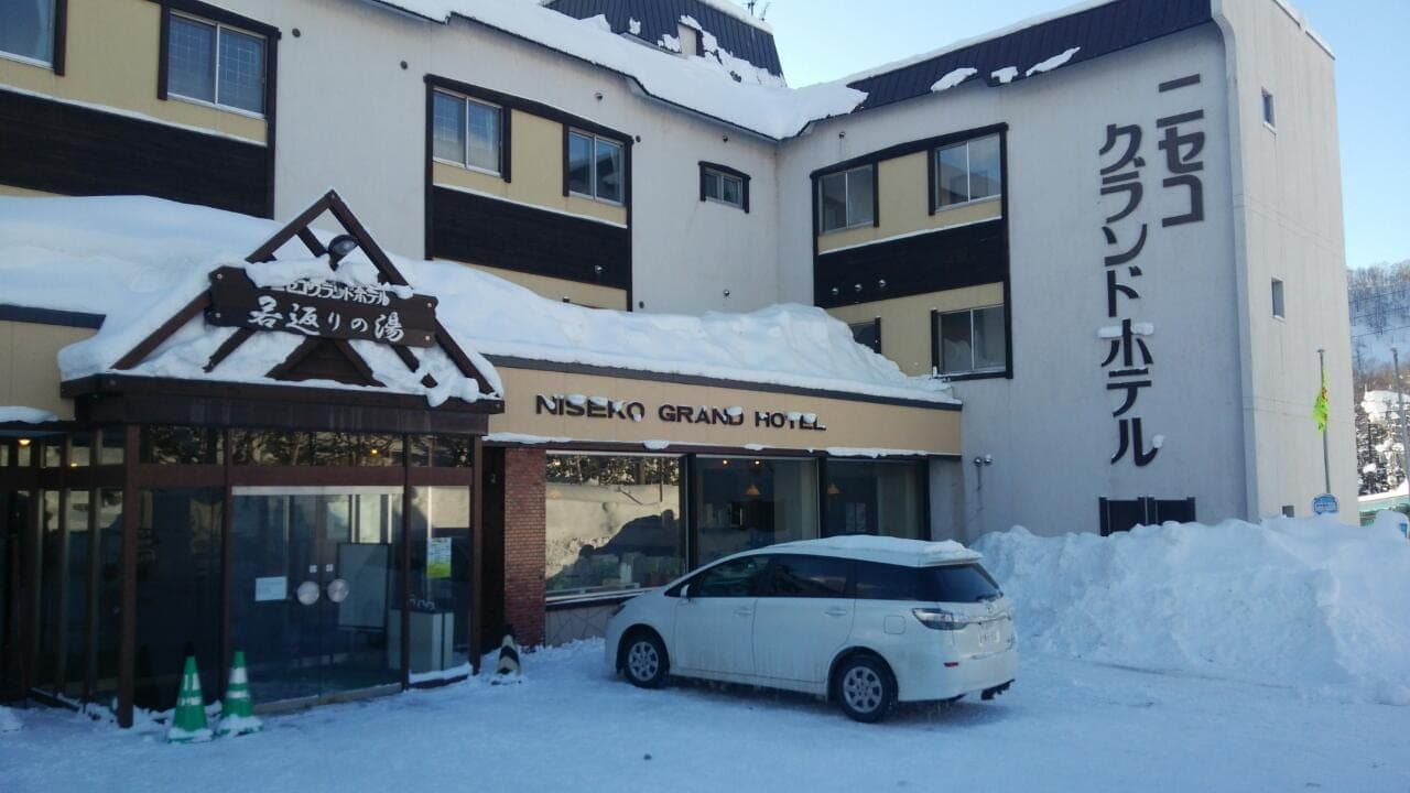 The entrance of Niseko Grand Hotel with snow banked along the driveway