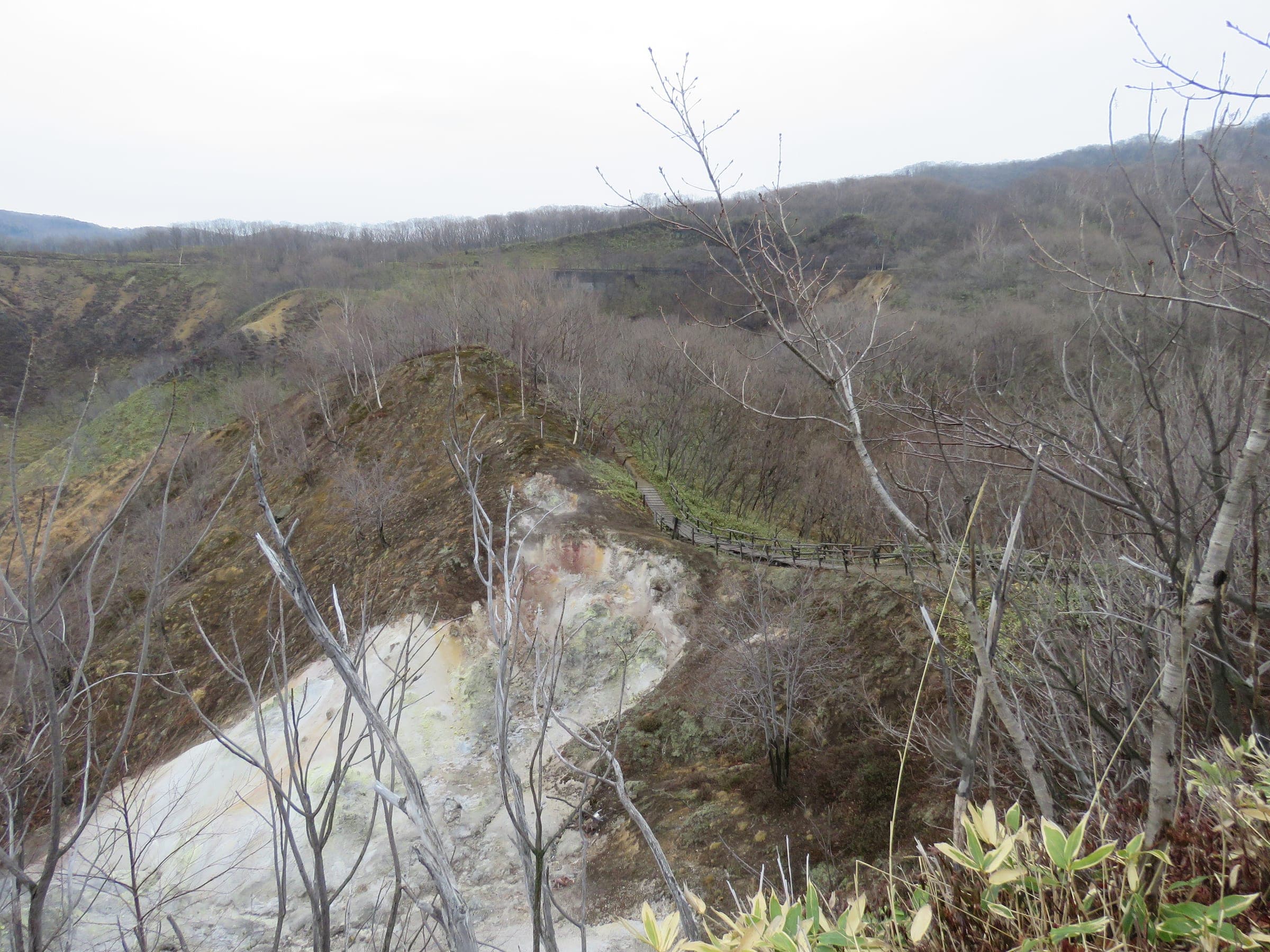 The Oyunuma crater pond seen through bare autumn trees from the lookout in Noboribetsu