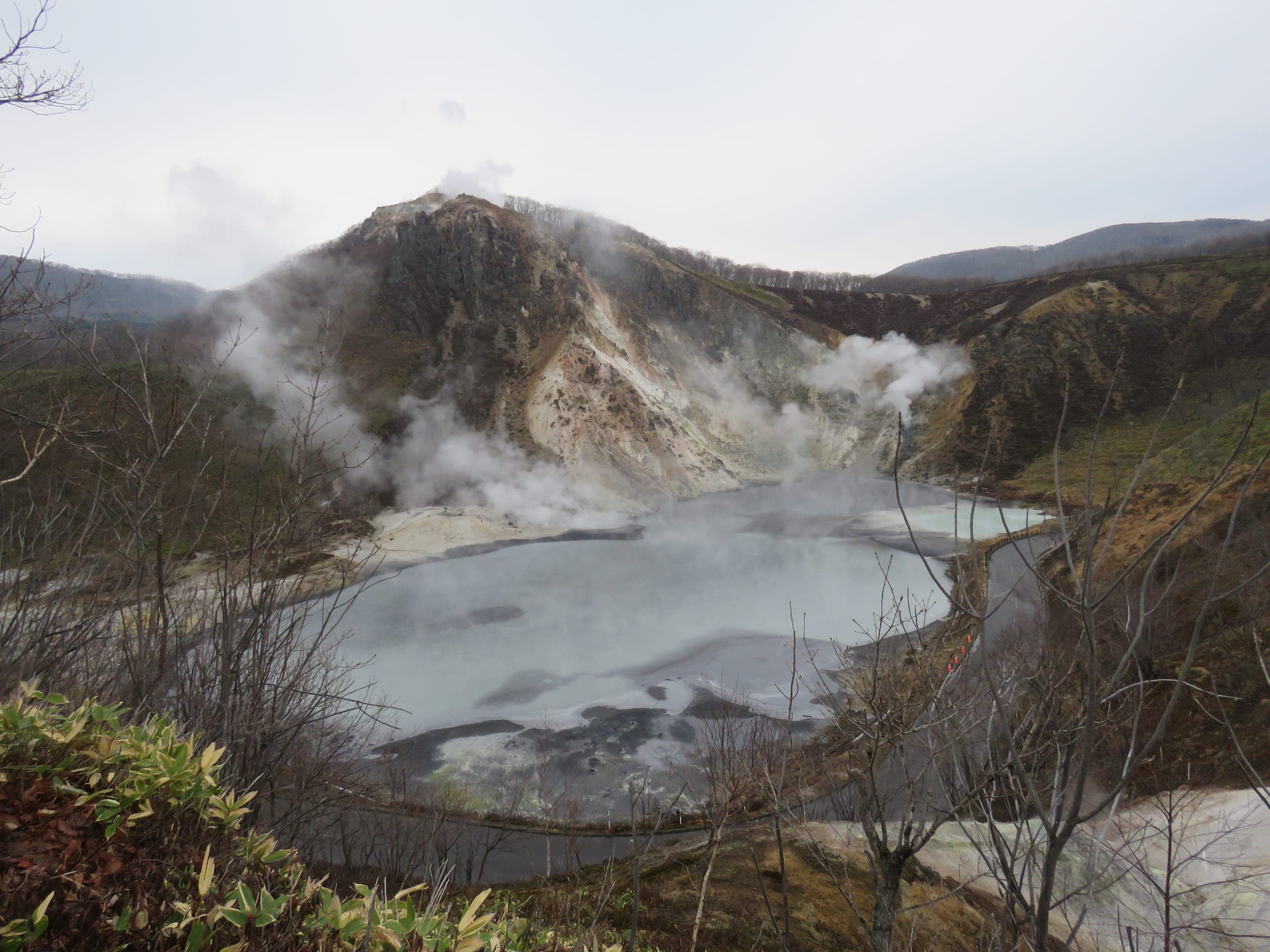 Steam rises off the grey Oyunuma crater pond below Mount Hiyori in Noboribetsu