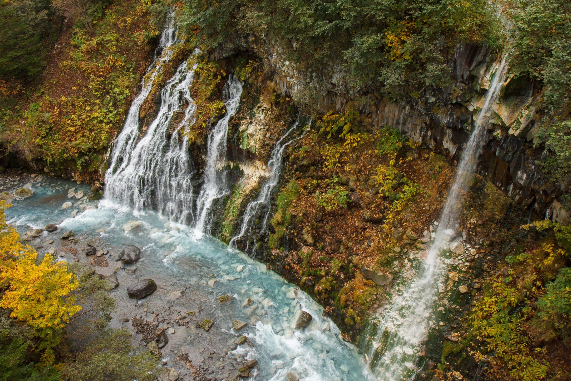 Shirahige Falls spills down a cliff of autumn foliage at Shirogane Onsen