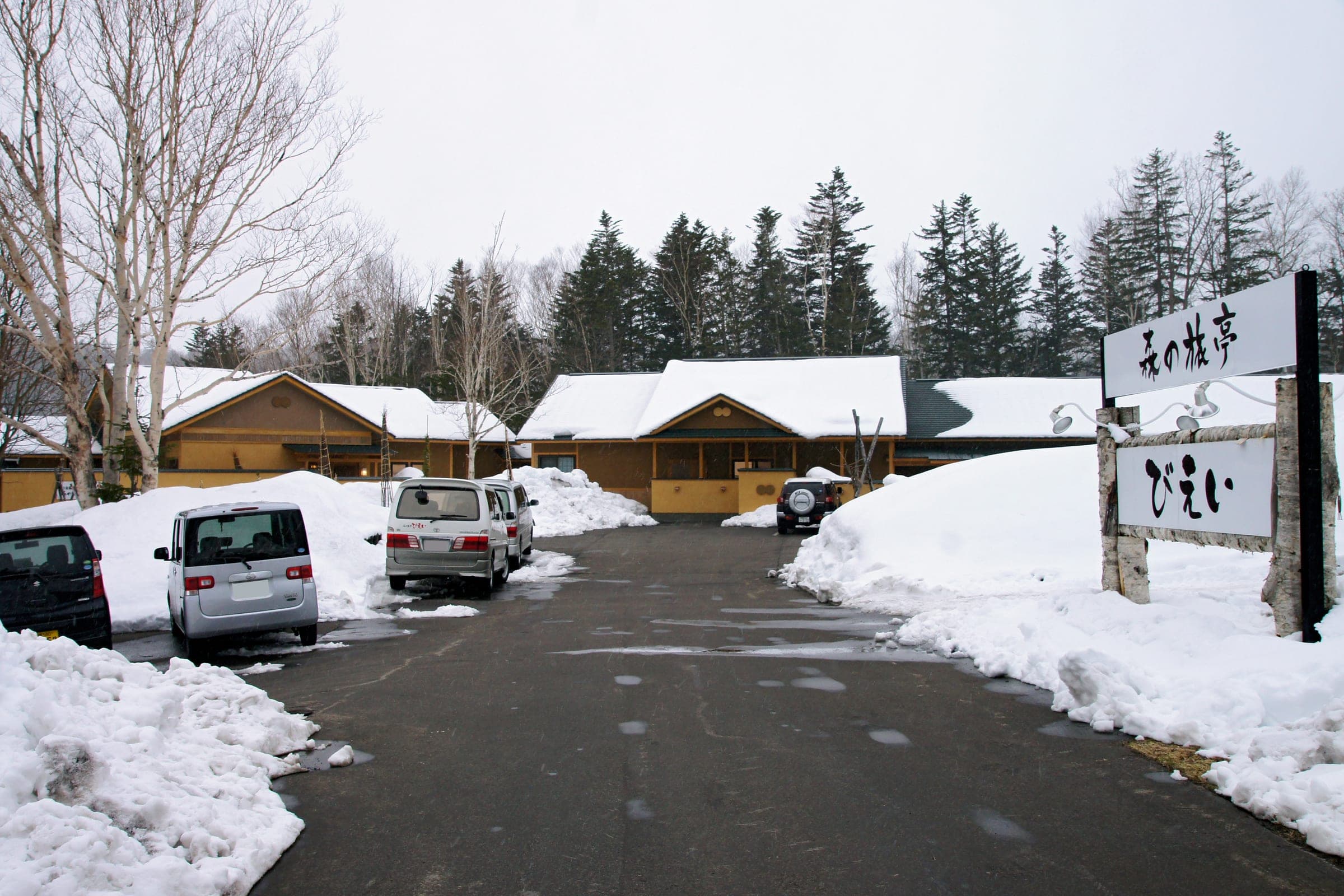 Snow banks line the drive to the low buildings of Mori-no-ryotei Biei at Shirogane Onsen