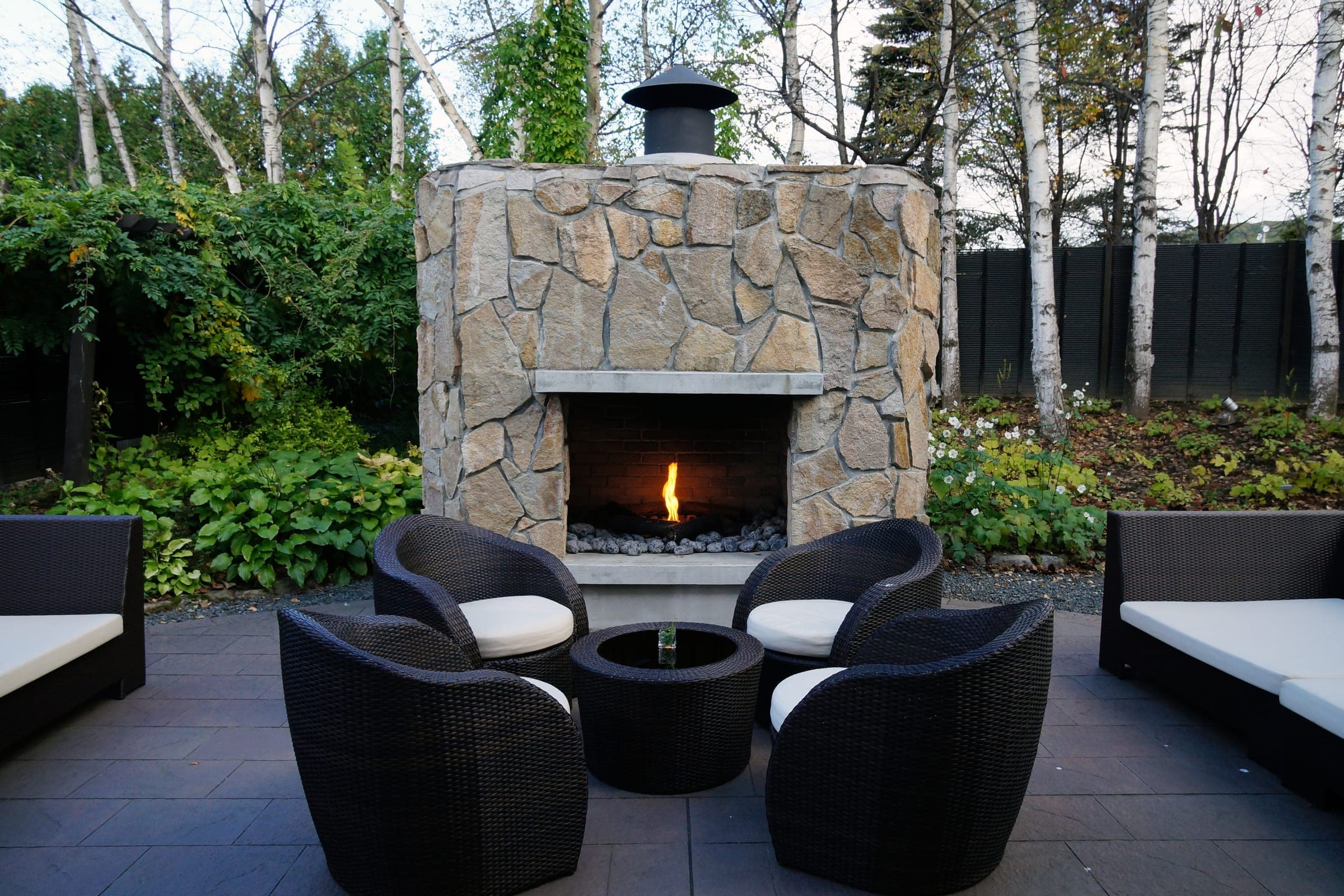 Wicker chairs gather round a stone outdoor fireplace at a Tokachigawa Onsen hotel