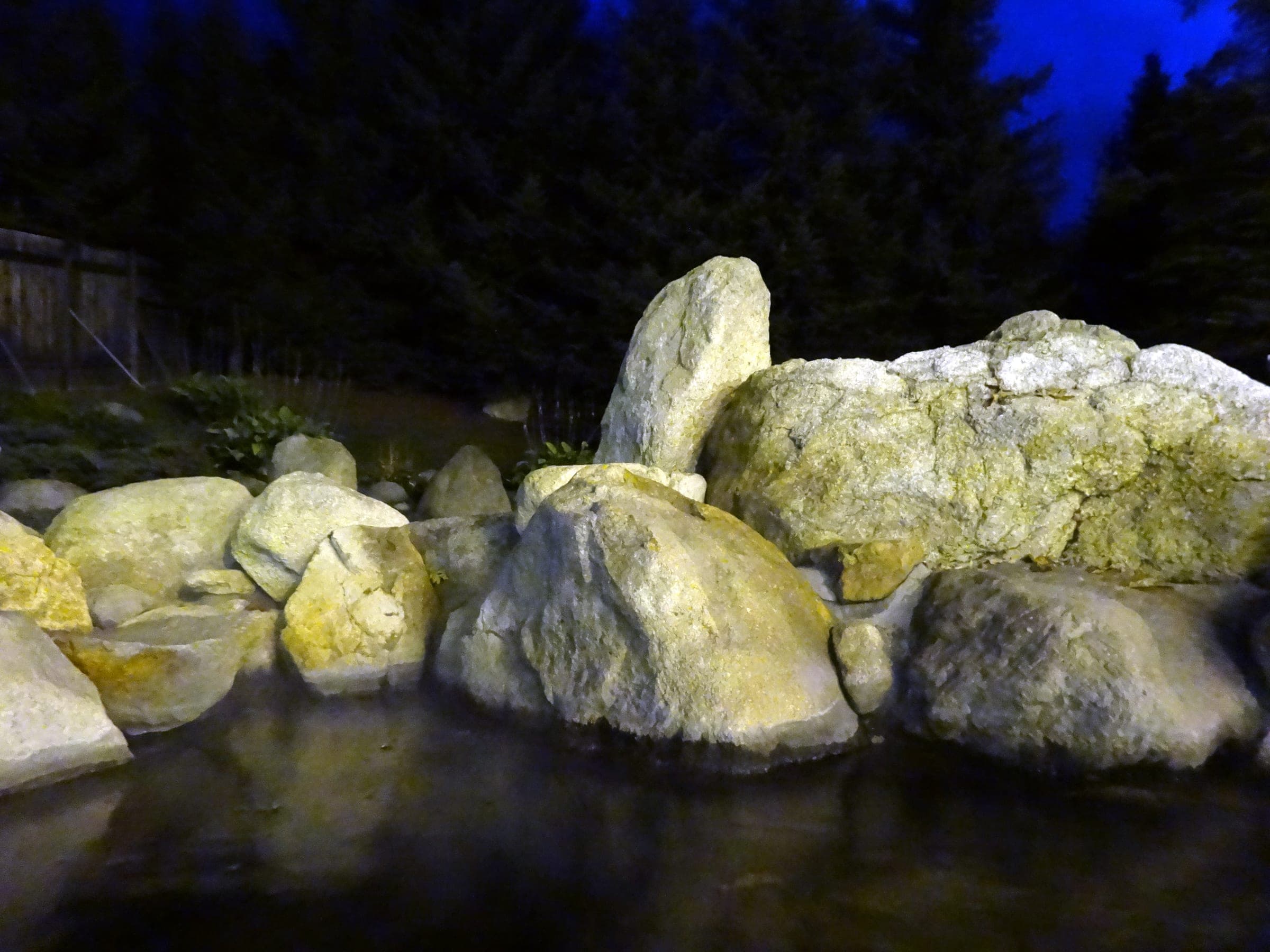 Floodlit boulders and still water in a hotel garden at Tokachigawa Onsen at night