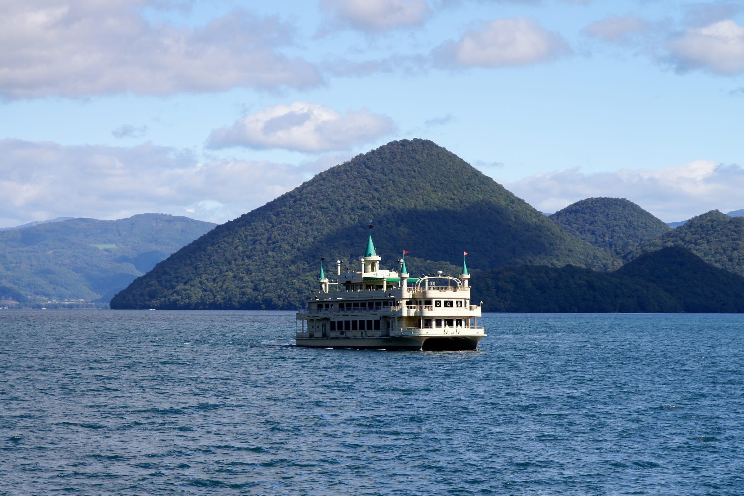A pleasure boat crosses Lake Toya in front of Nakajima island, seen from Toyako Onsen