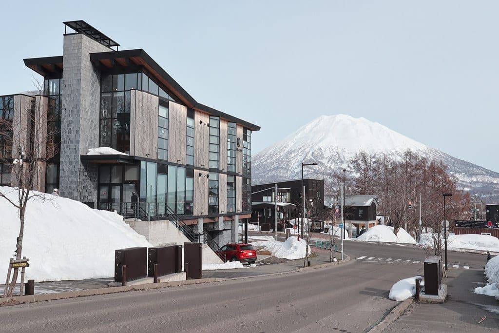 Mt. Yotei rises above snowbanks and new buildings on a lower Hirafu street near Yukoro Onsen