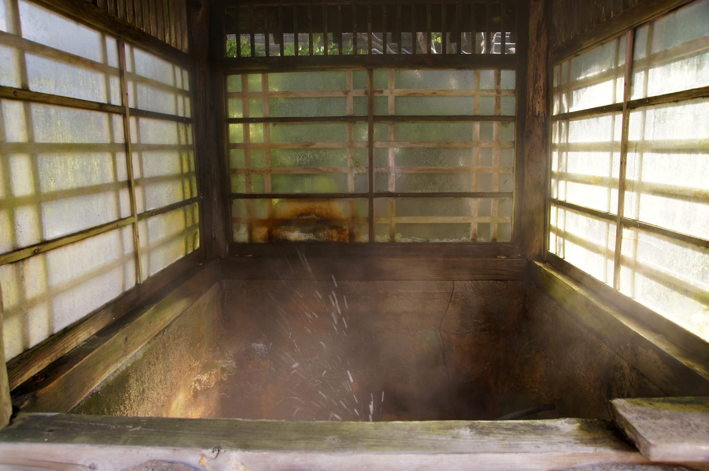 Morning light falls on a wooden bath through shoji screens at Wakamatsu in Yunokawa