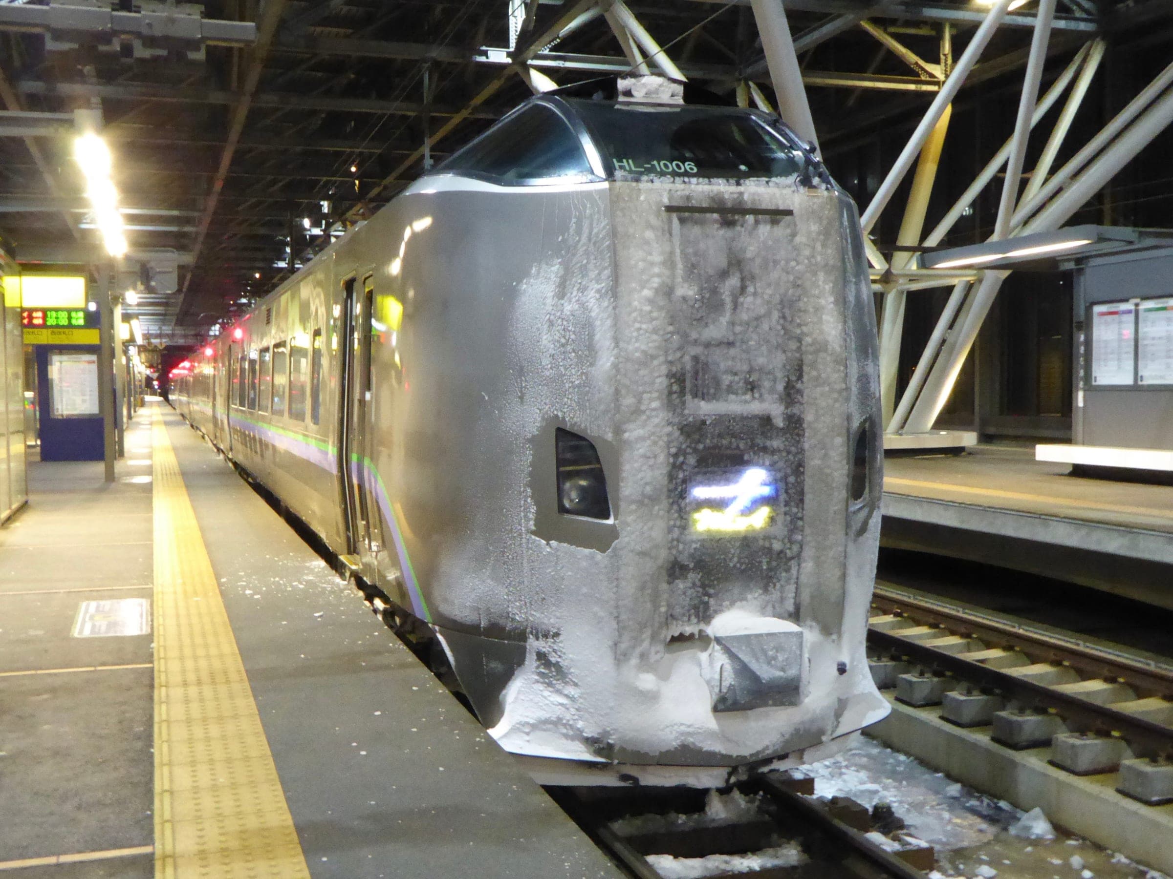 Snow cakes the nose of a JR Hokkaido 789 series Kamui express at a station platform