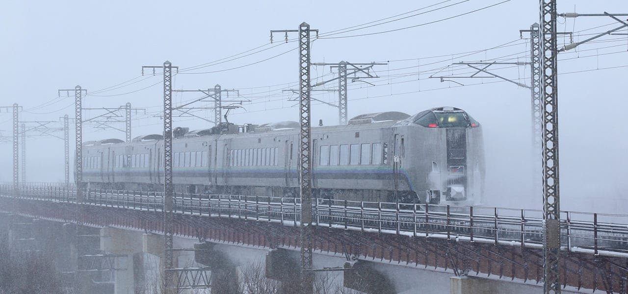 A JR Hokkaido 789 series express crosses the Yubari River bridge near Ebetsu in falling snow
