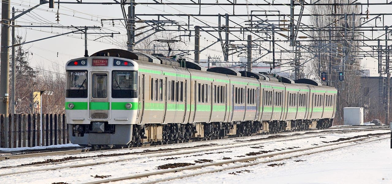 A JR Hokkaido 721 series Rapid Airport train runs past snow in Sapporo