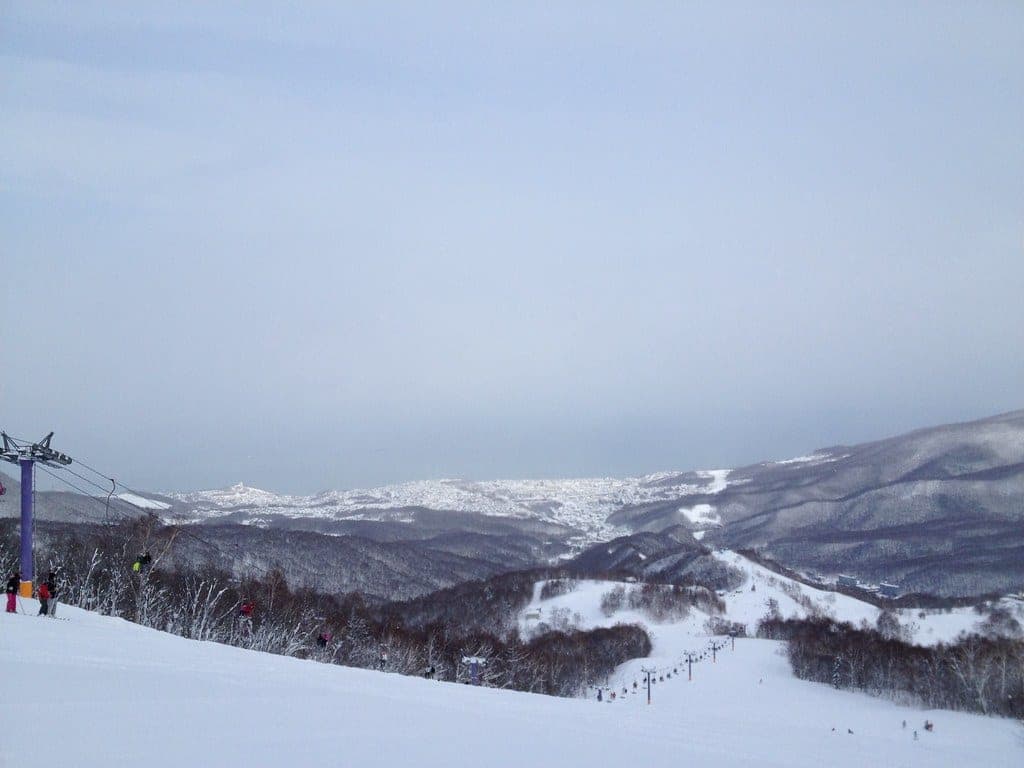 Asarigawa Onsen ski runs drop away below the top of the Purple lift on a clear winter day