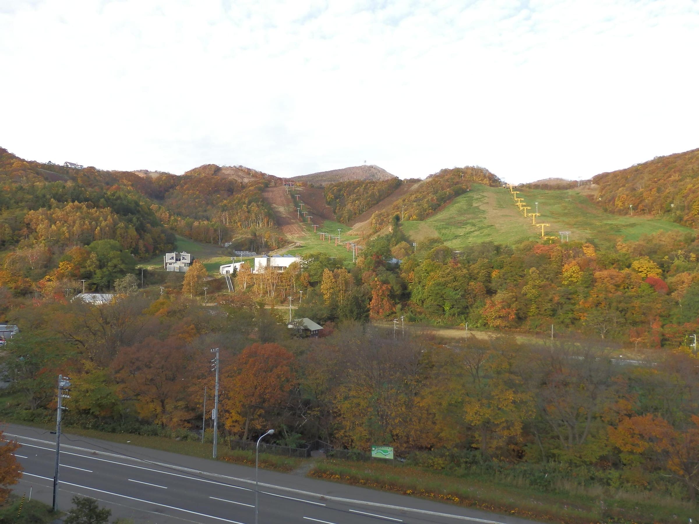 Asarigawa Onsen Ski Resort cuts green lanes through autumn forest above the valley before the first snow