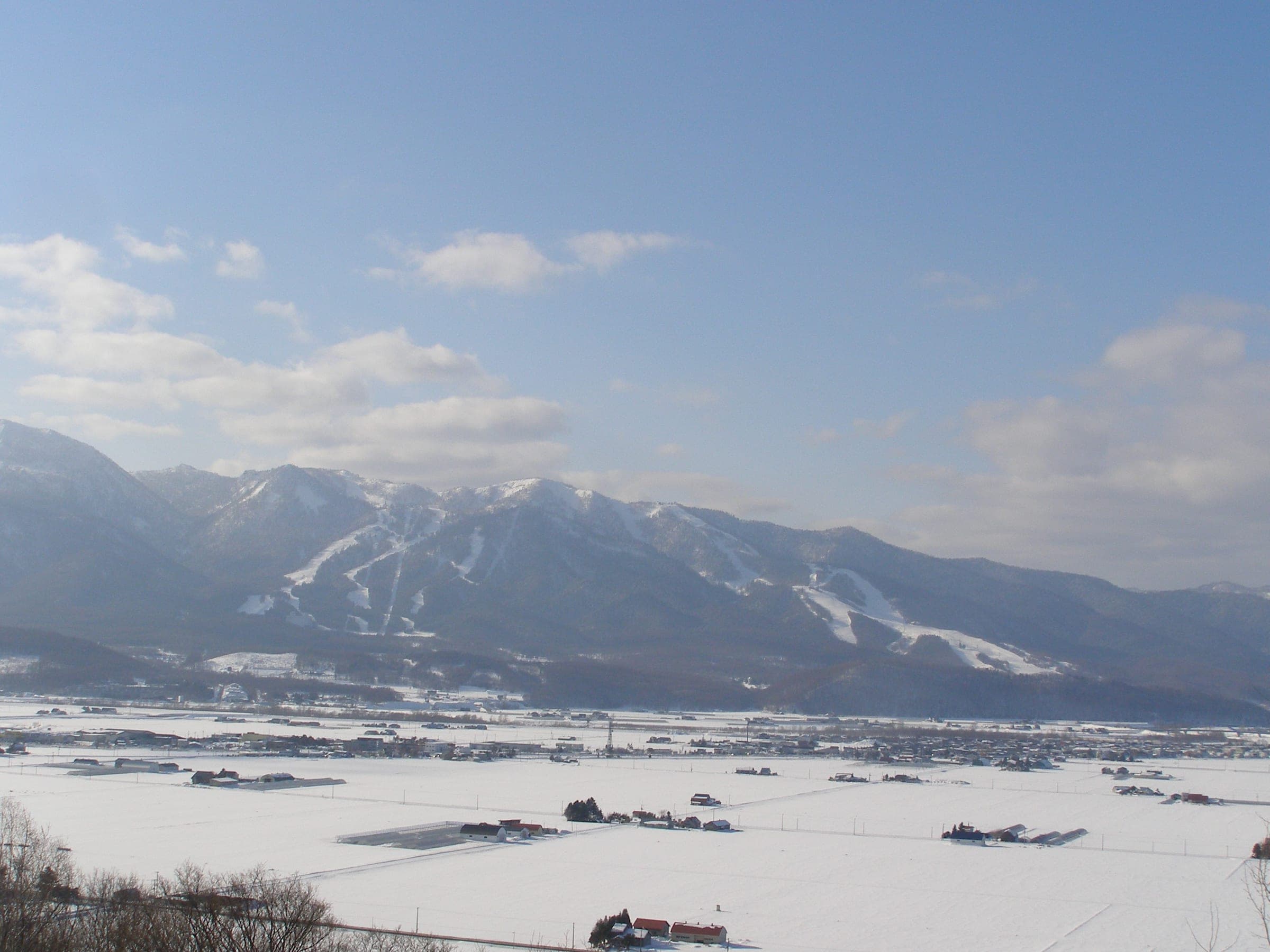 Furano Ski Resort's runs streak the mountains above snowy farmland on the basin floor