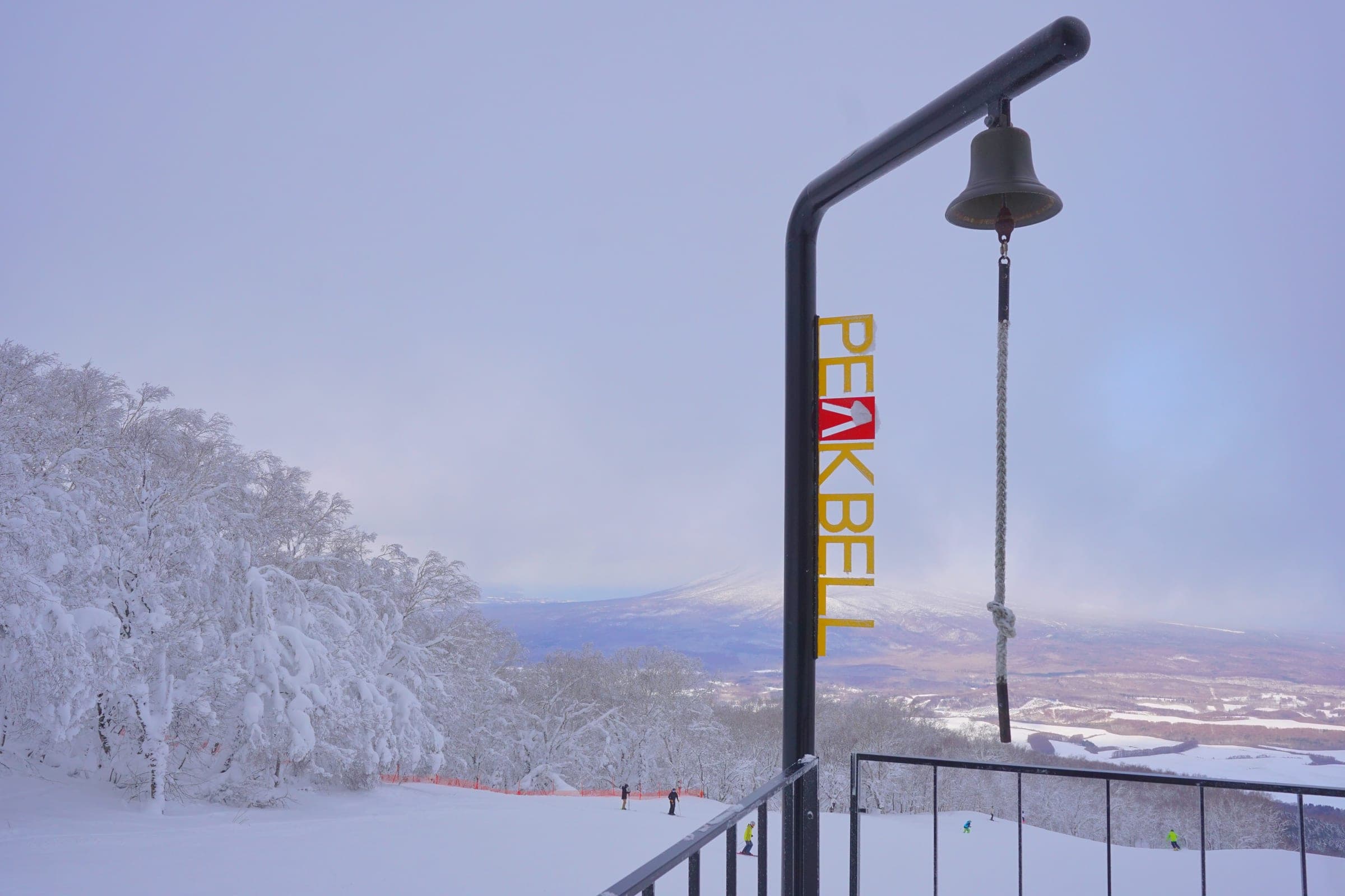 The Peak Bell stands at the top of Hakodate Nanae Snowpark beside snow-covered trees