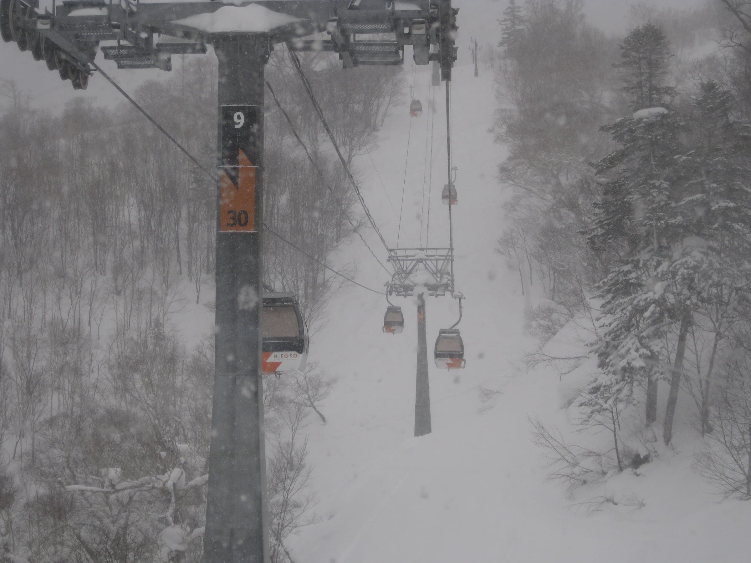 Kiroro's gondola climbs through snow-laden forest during heavy snowfall
