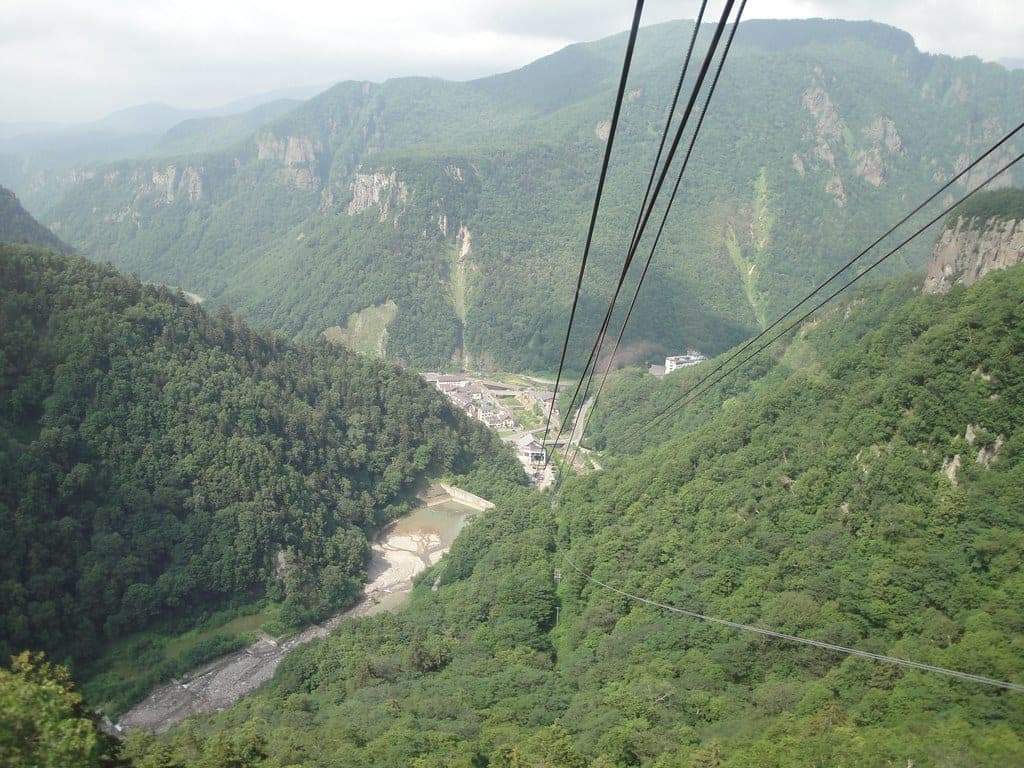 The Kurodake Ropeway cables run high above the green floor of Sounkyo gorge
