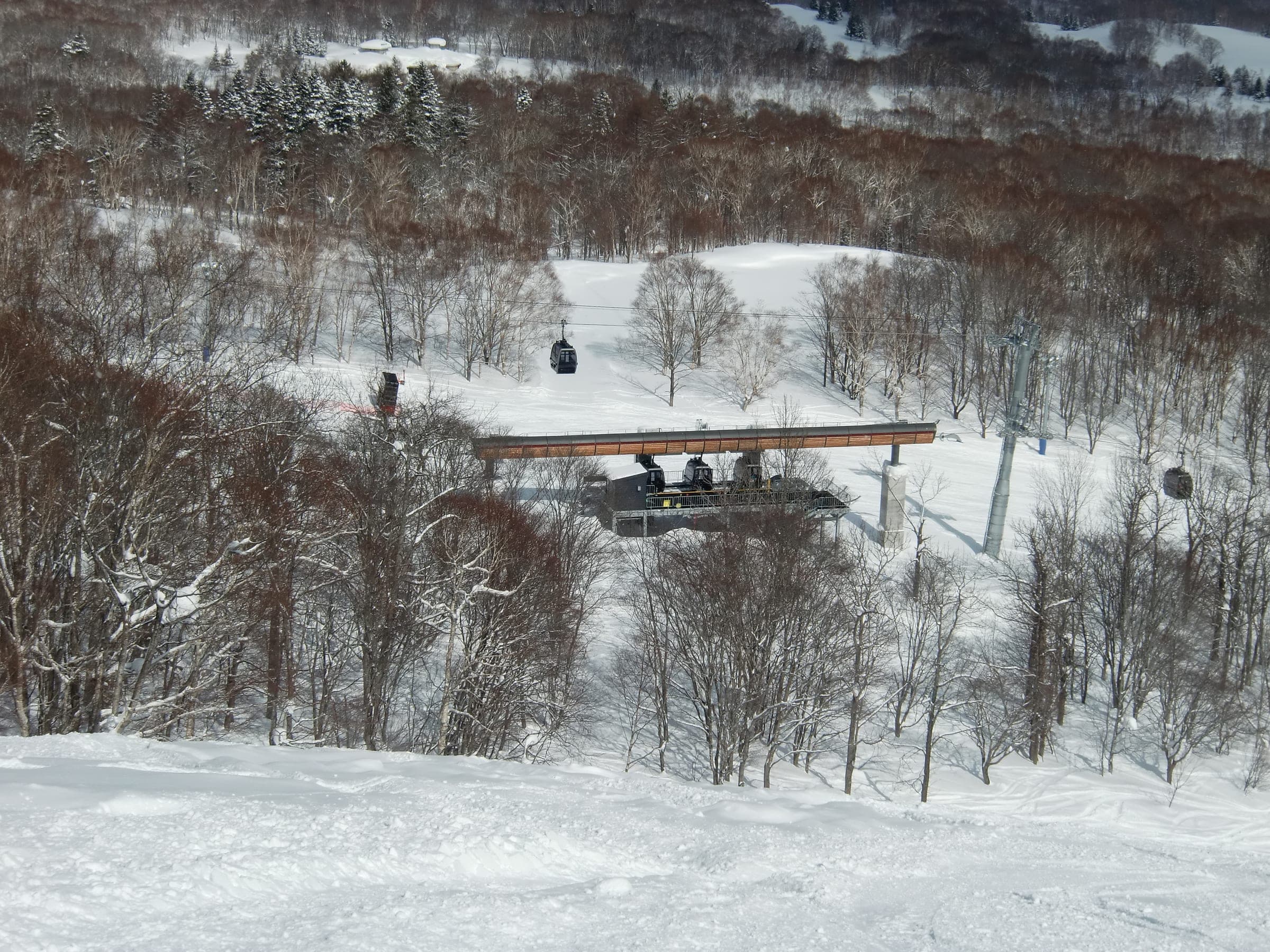Gondola cabins pass the intermediate station in snowy forest at Niseko HANAZONO