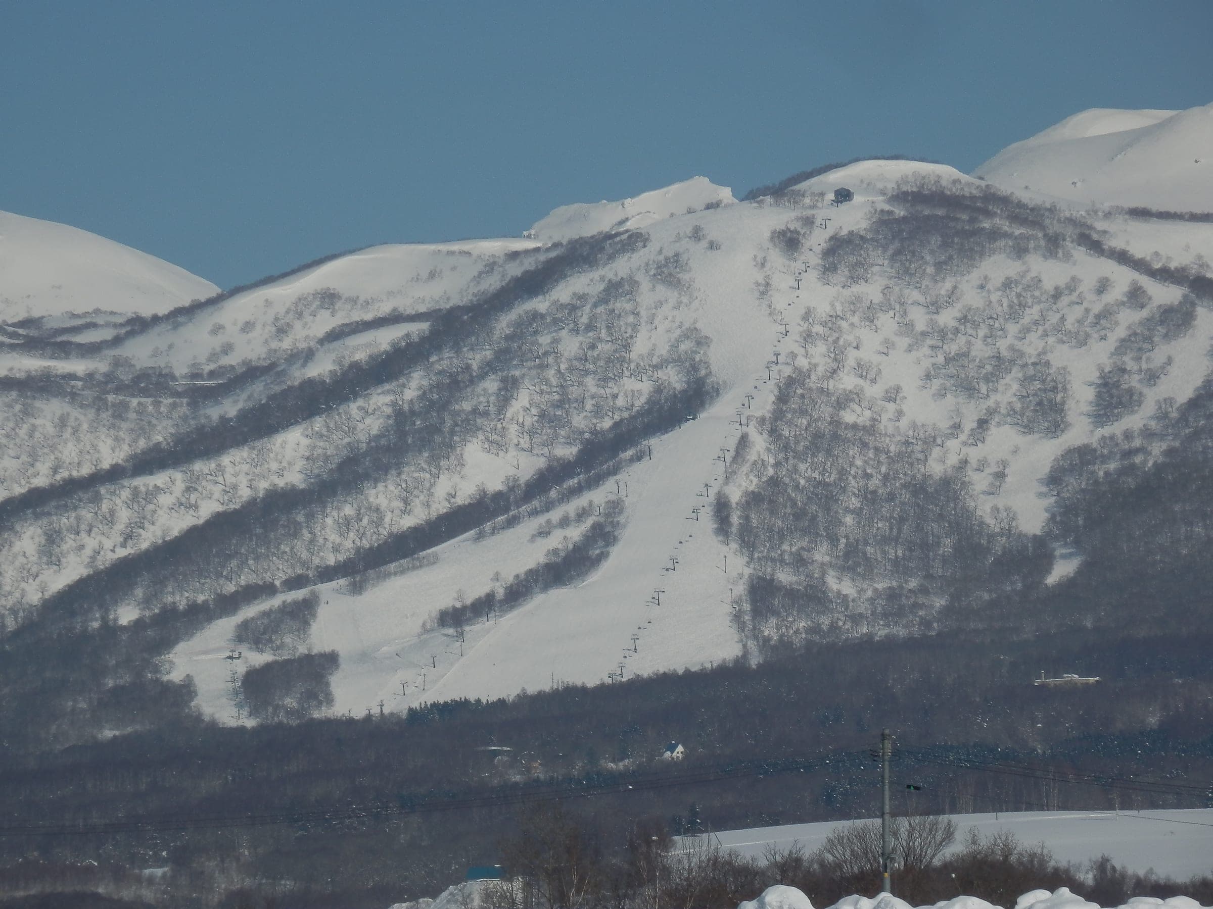 Niseko Moiwa's ski runs stand under winter snow above the Konbu Onsen area, home of Hotel Kanronomori