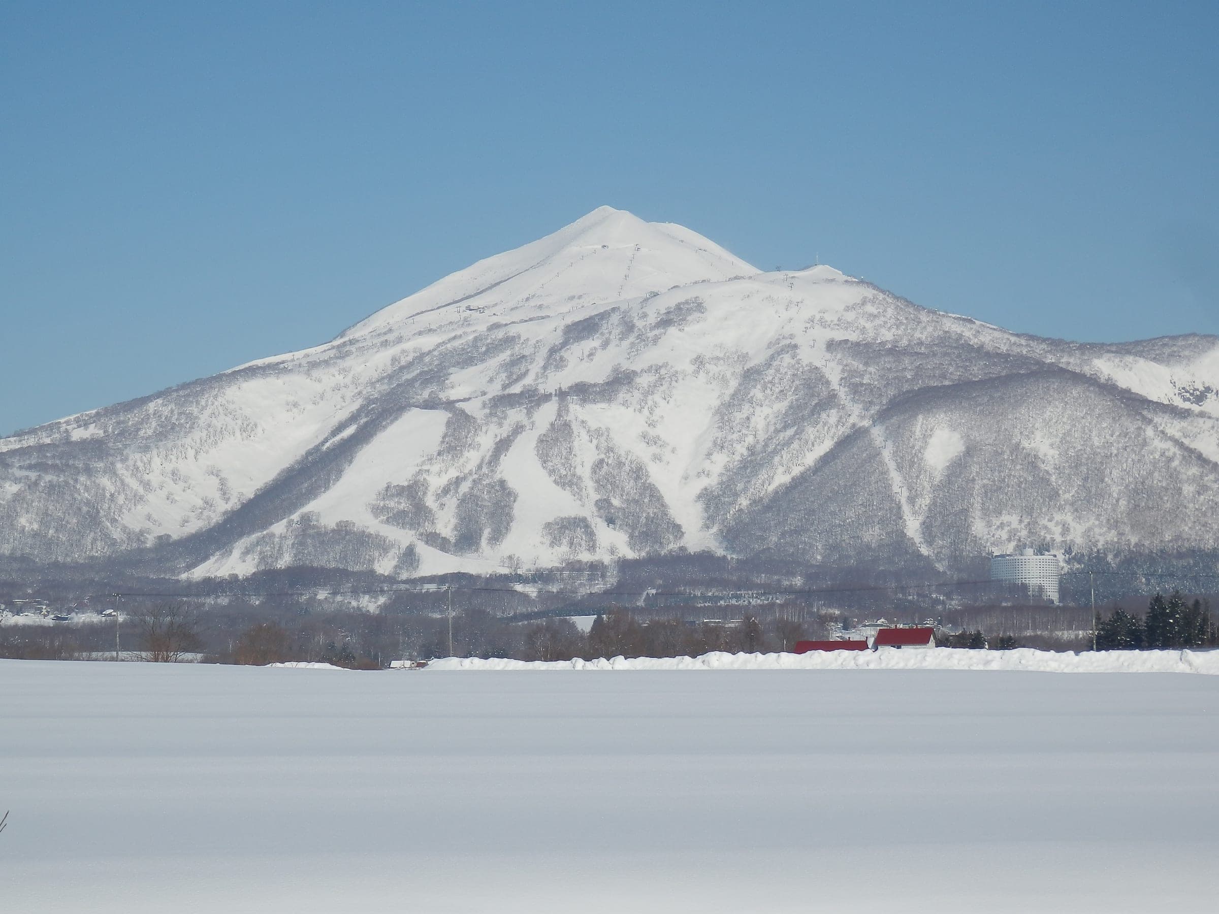 The snowy southeast face of Niseko Annupuri rises above white fields on the Niseko Village side