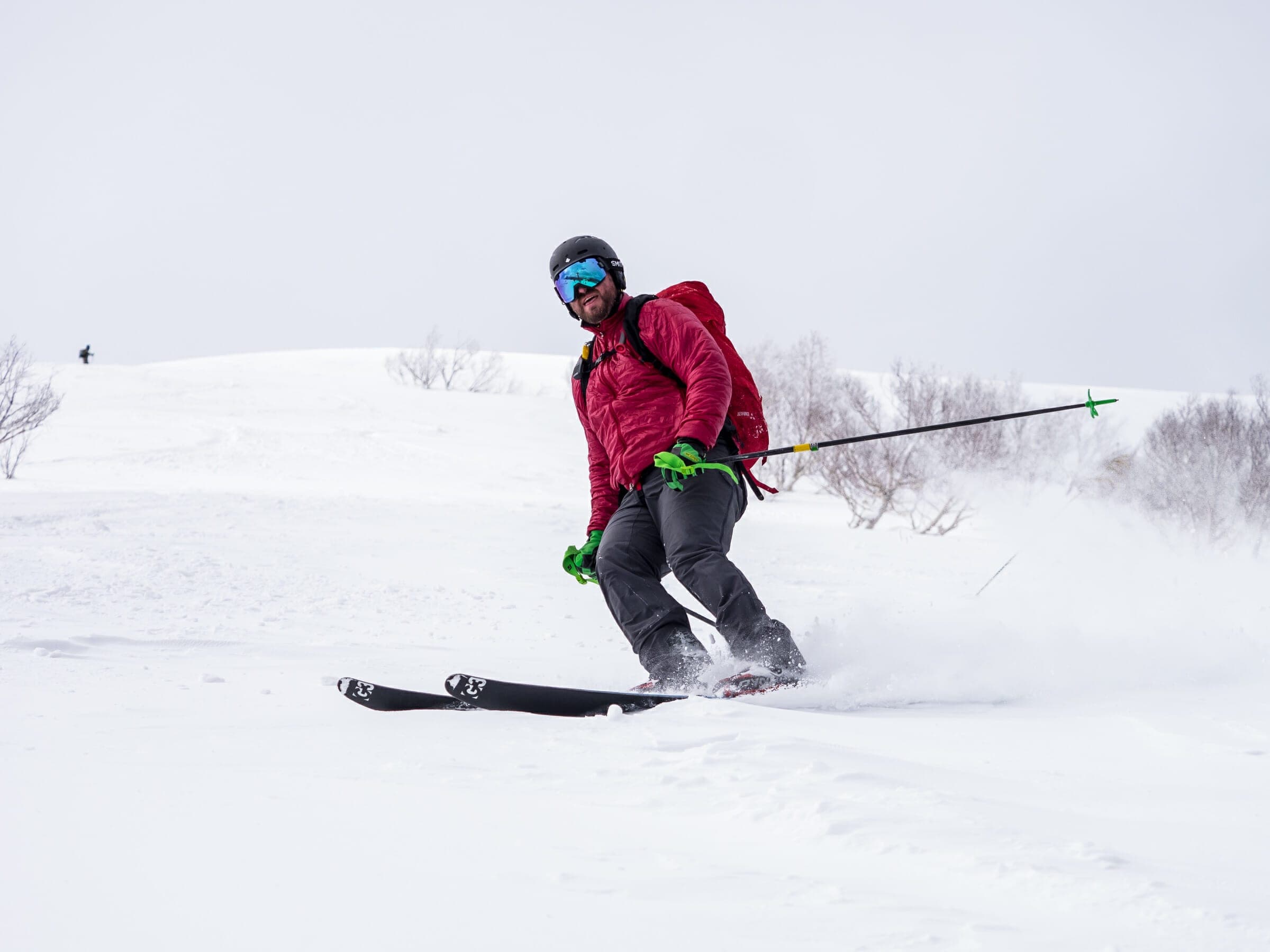 A skier in a red jacket carves a turn in fresh snow on the open slopes of Weisshorn