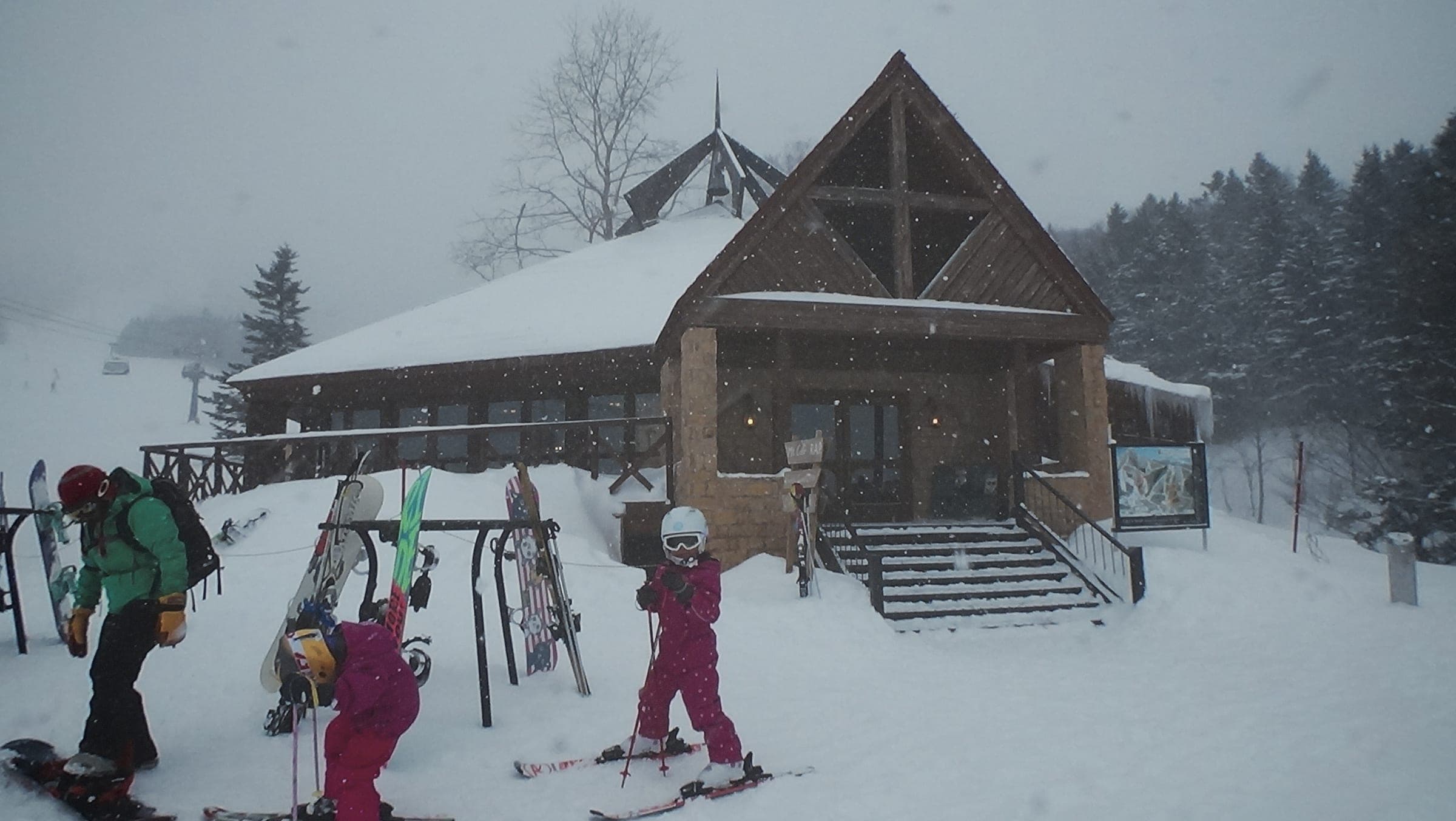 Skiers gather outside the log-built Mt. Cafe RAP in falling snow at Hoshino Resorts Tomamu