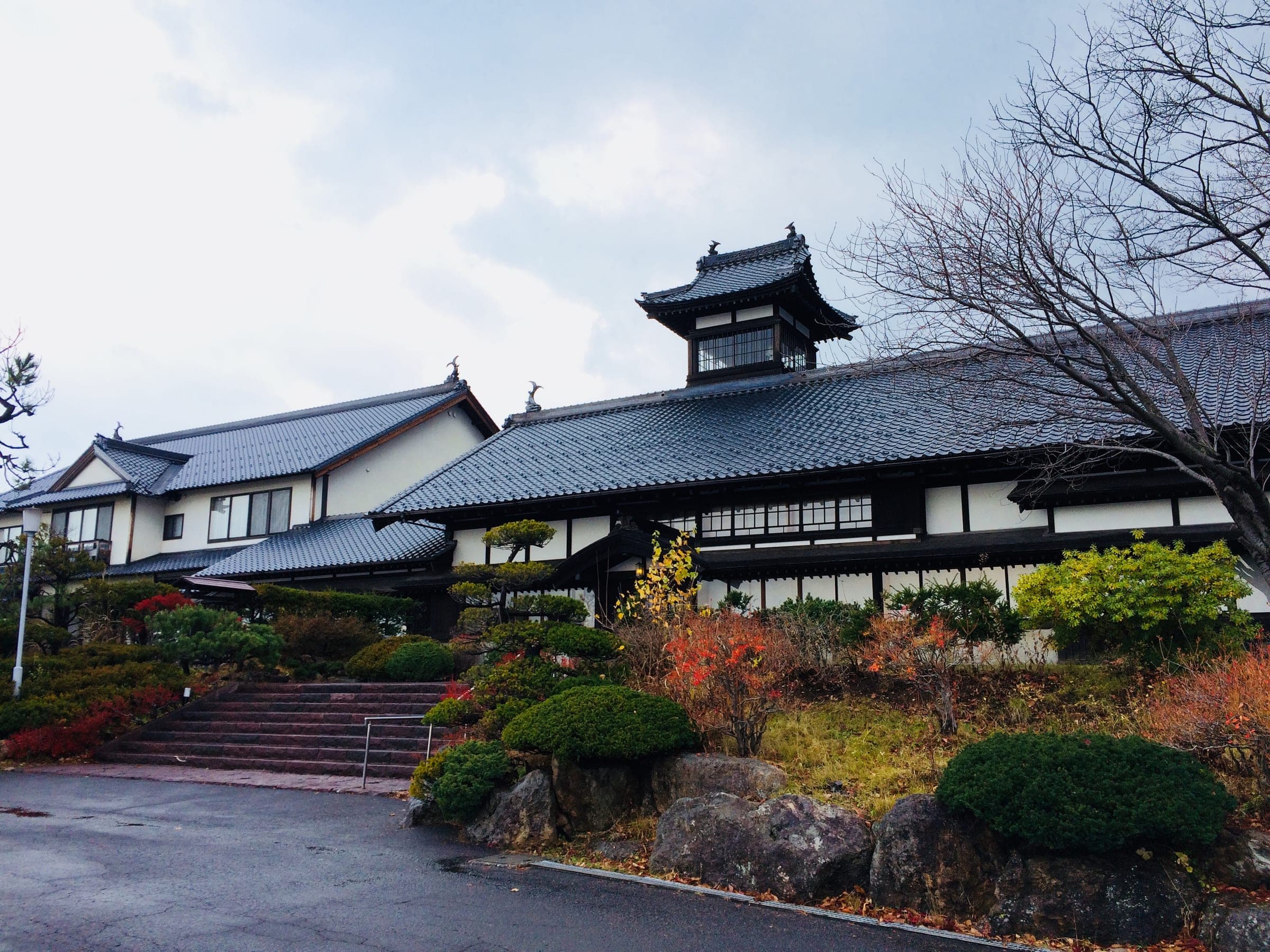 Ginrinsou's tiled roofs and lookout tower above stone steps and autumn gardens in Otaru